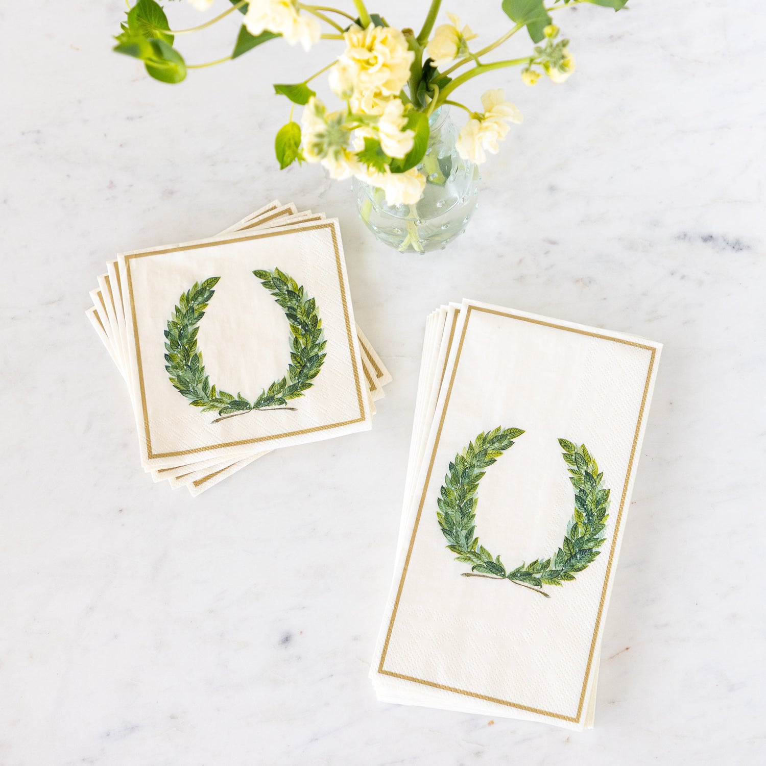 Laurel Wreath Cocktail and Guest Napkins next to a vase of flowers.