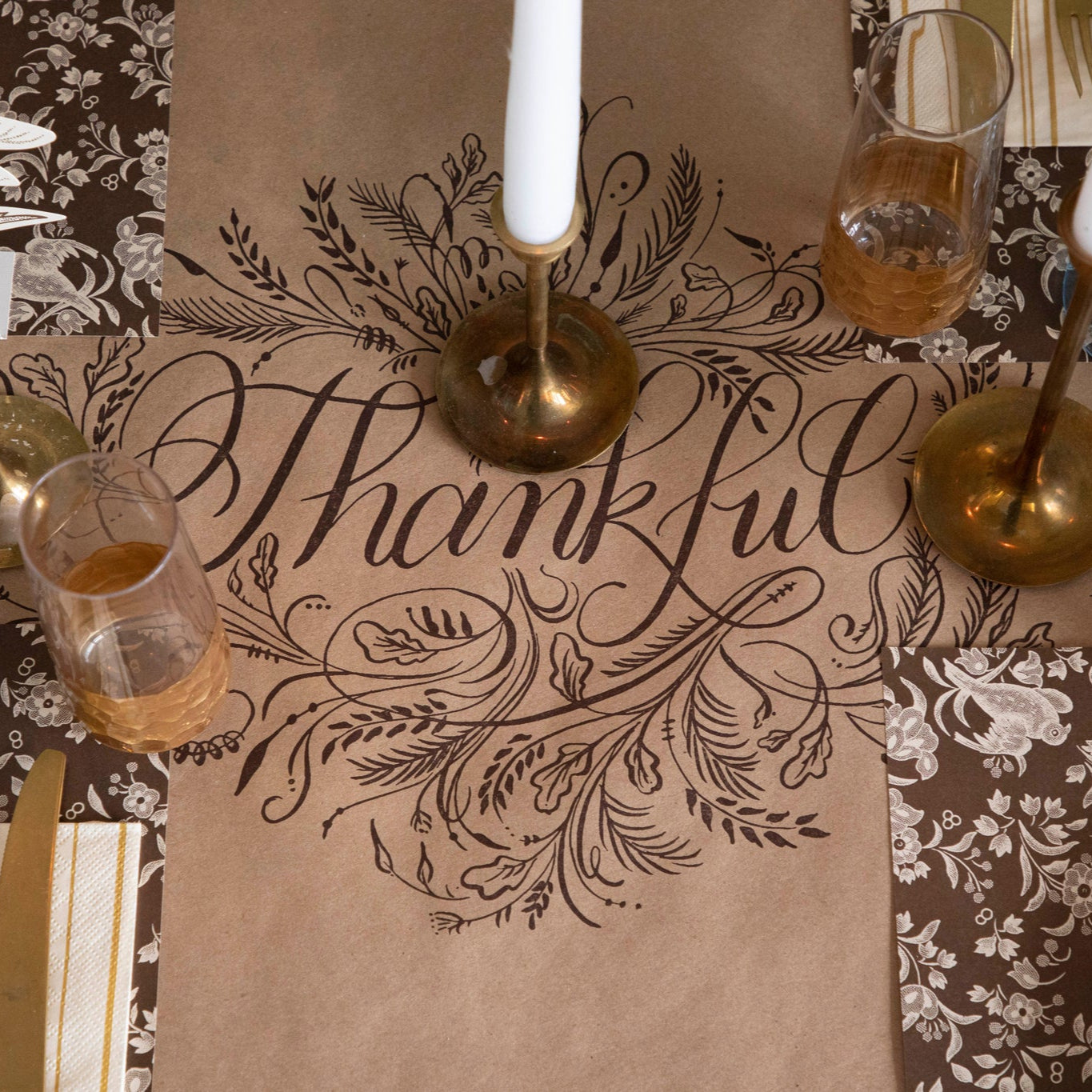 Thankful Runner under a fall table setting with Burleigh Brown Regal Peacock Placemats, candles in gold candle holders, and gold rimmed glasses.
