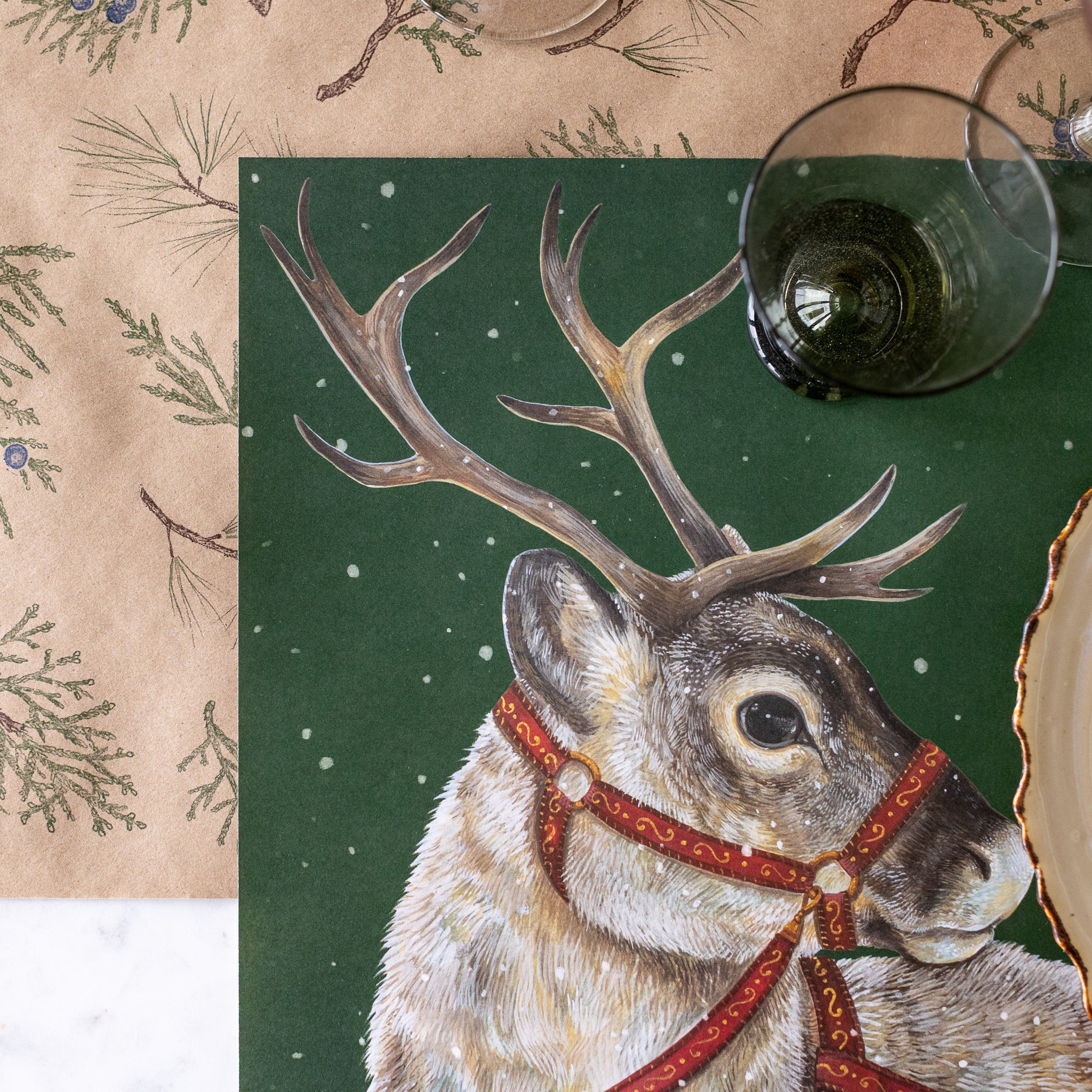 Placemat with reindeer design on a table setting with wine glasses.