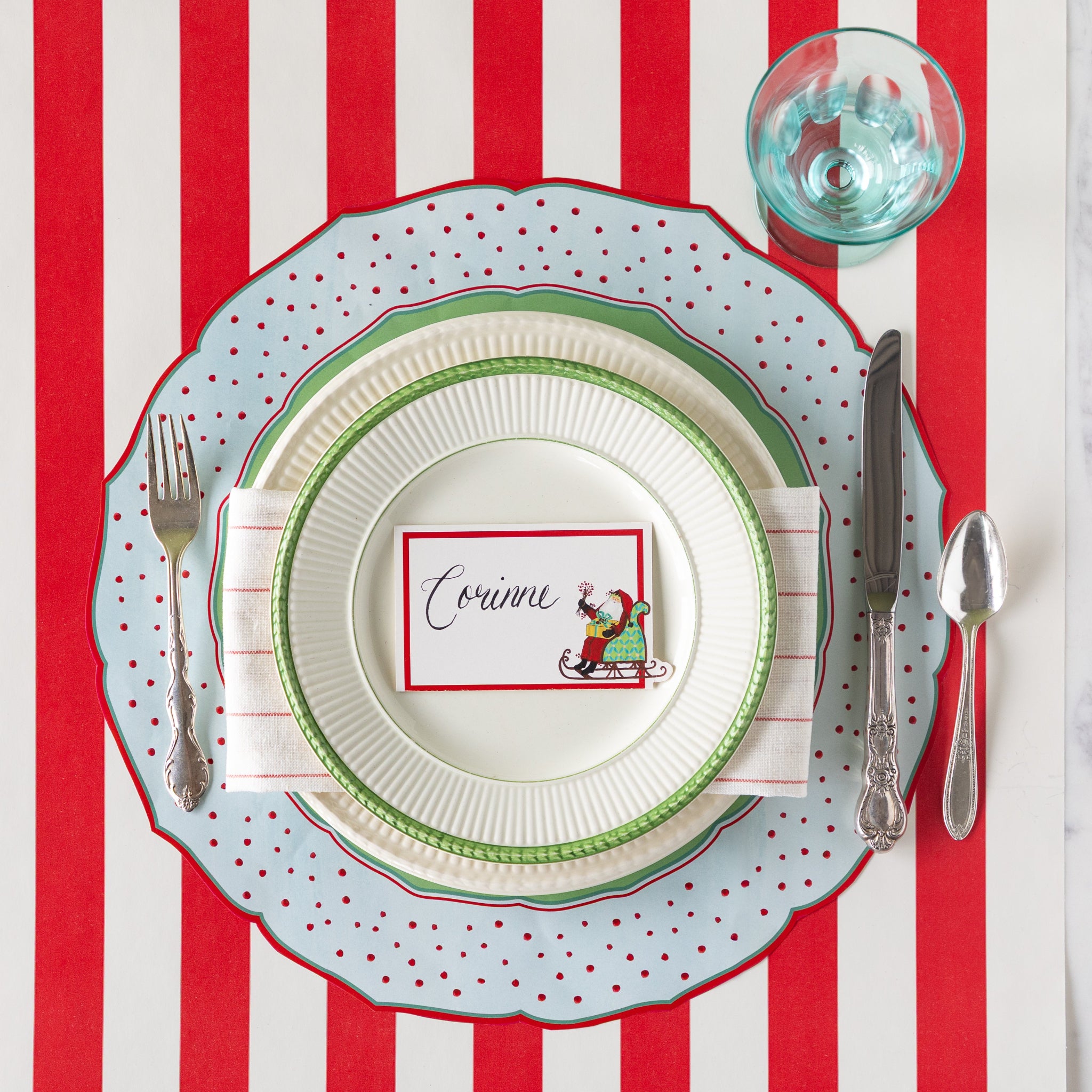 Christmas-themed place setting with the Die-cut Old St. Nick Placemat, vintage dinnerware with Old St. Nick Place Card atop, on the Red Classic Stripe Runner.