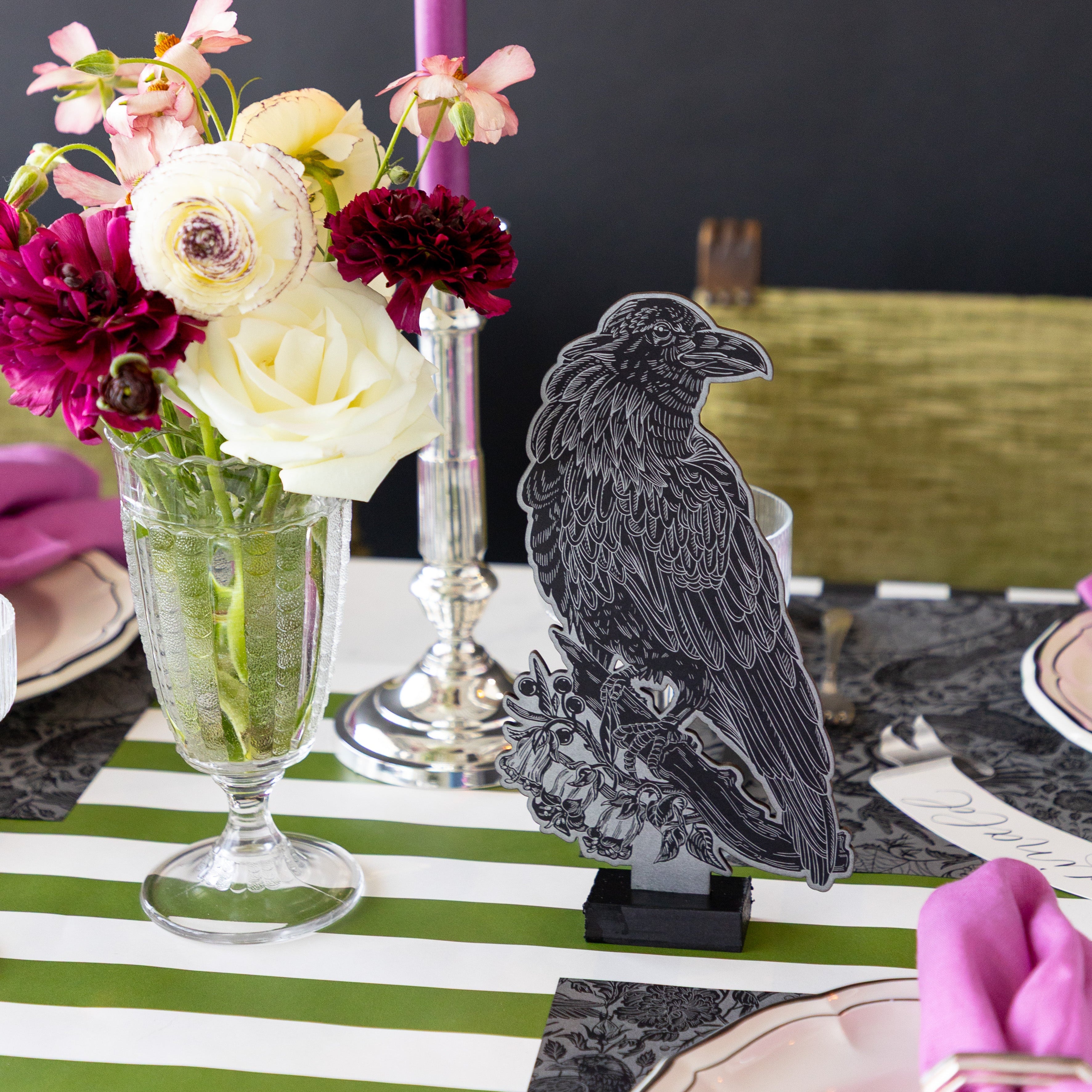 The Raven Table Ornament behind a place setting featuring the Raven Toile Placemat, flowers and Moss Green Classic Stripe Placemat underneath.