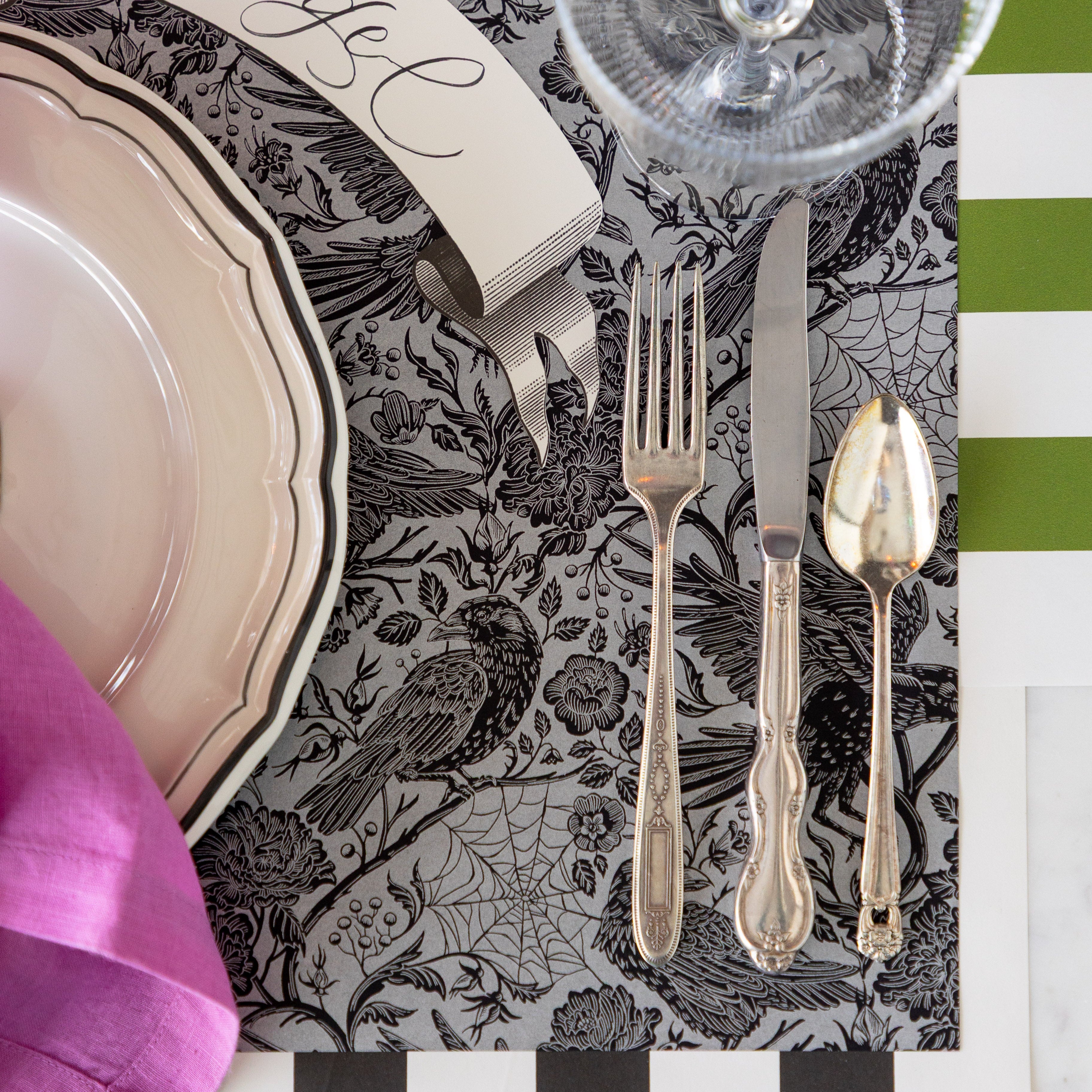 A place setting featuring the Raven Toile Placemat with the Moss and Black Classic Stripe Runners underneath.