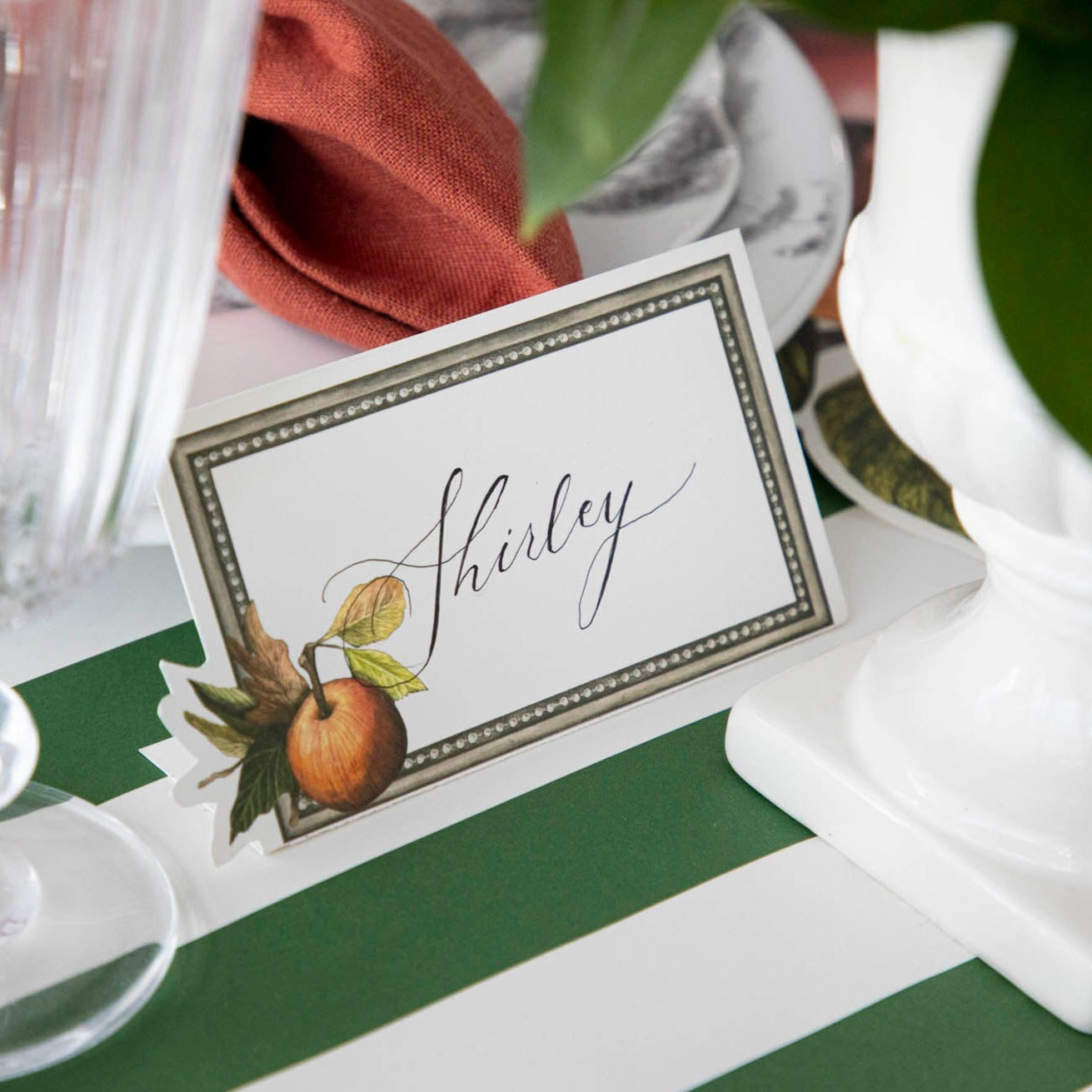 Close-up of a Heirloom Apples Place Card labeled "Shirley" as part of an elegant table setting.