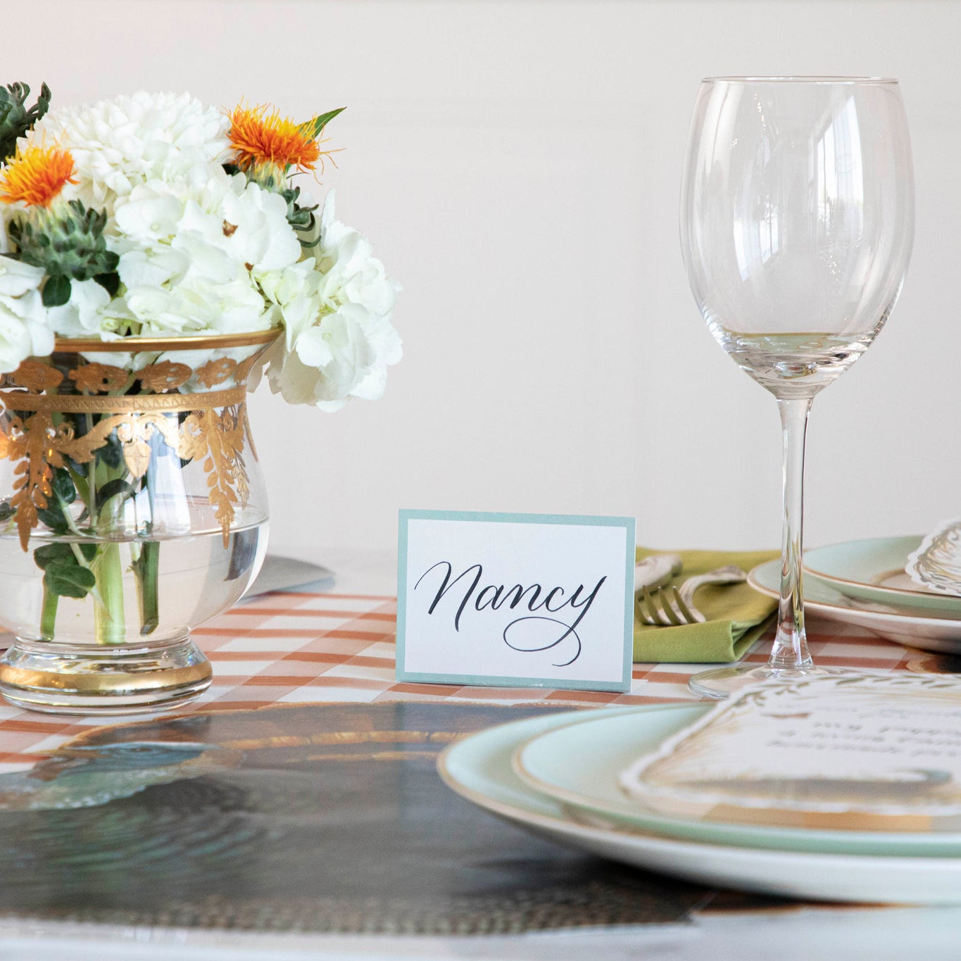 Seafoam Place Card reading &quot;Nancy&quot; behind a Thanksgiving place setting.