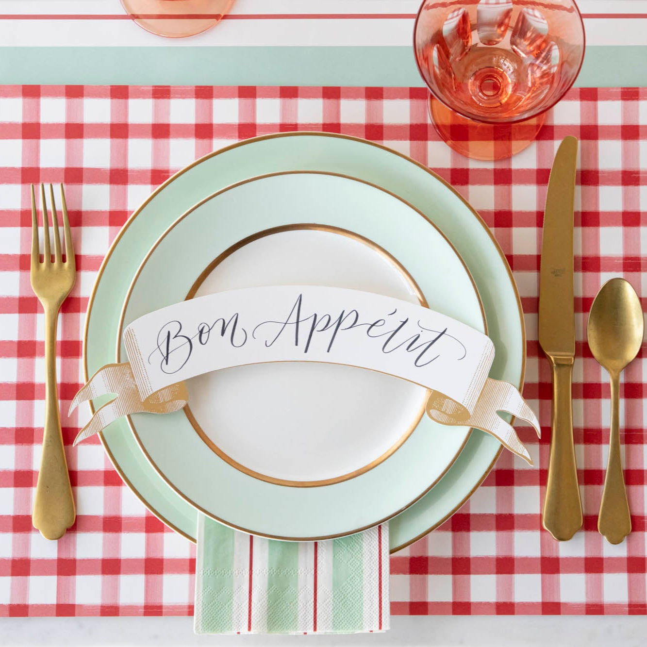 Classic Gold Banner Table Accent with "Bon Appetit" written on it, on the dinner plates of a place setting.