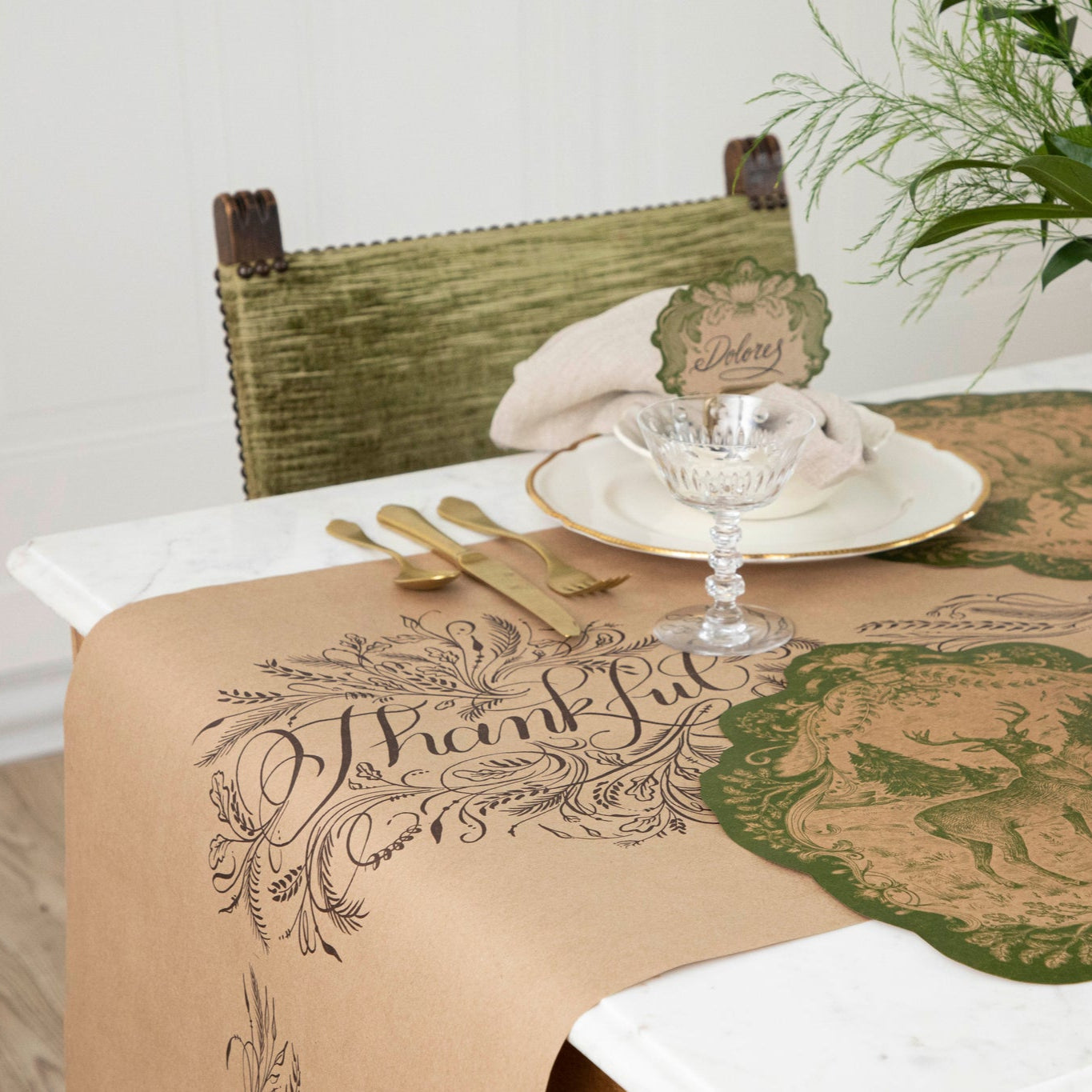 The Thankful Runner rolled over the end of a table, under a fall table setting with florals and Moss Fable Toile Placemats.