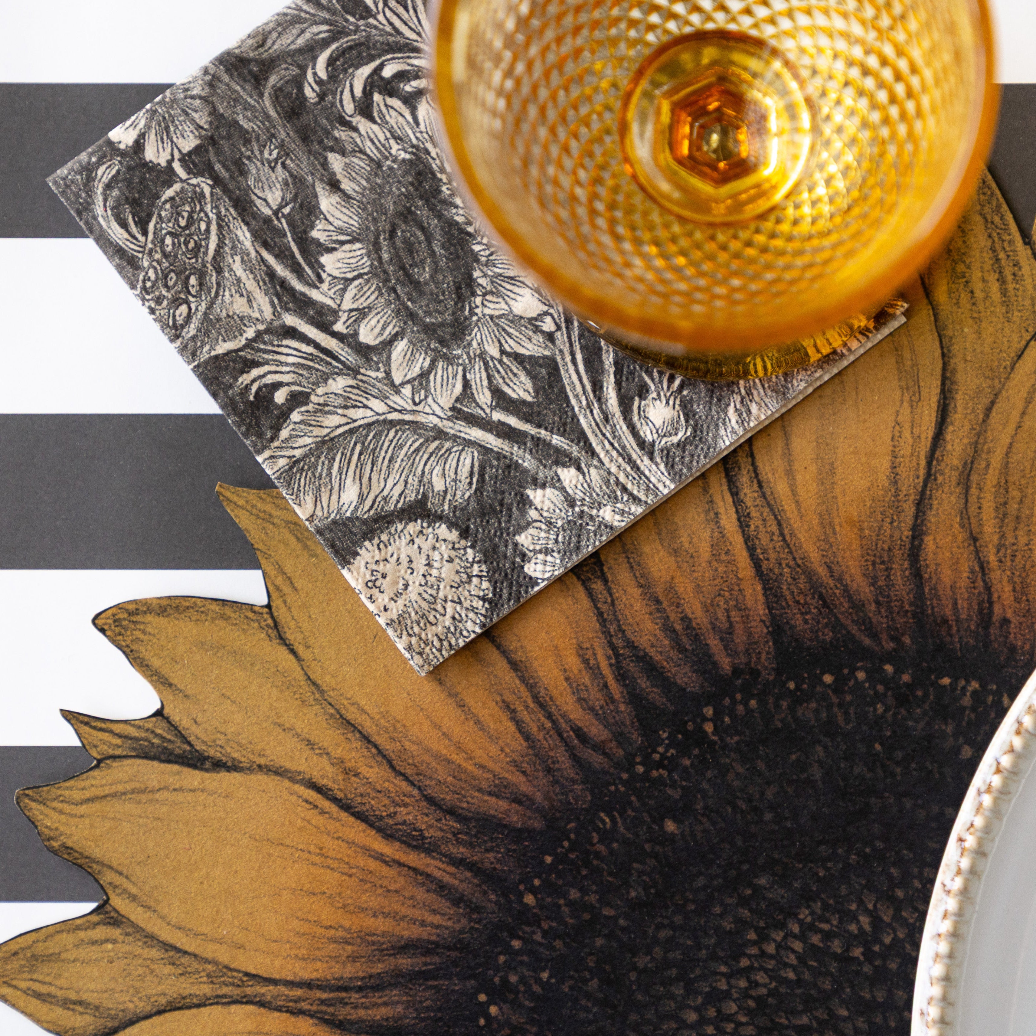 Vintage Sunflower Cocktail Napkin under an orange glass, on top of the Die-cut Vintage Sunflower Placemat with Black Classic Stripe Runner underneath.