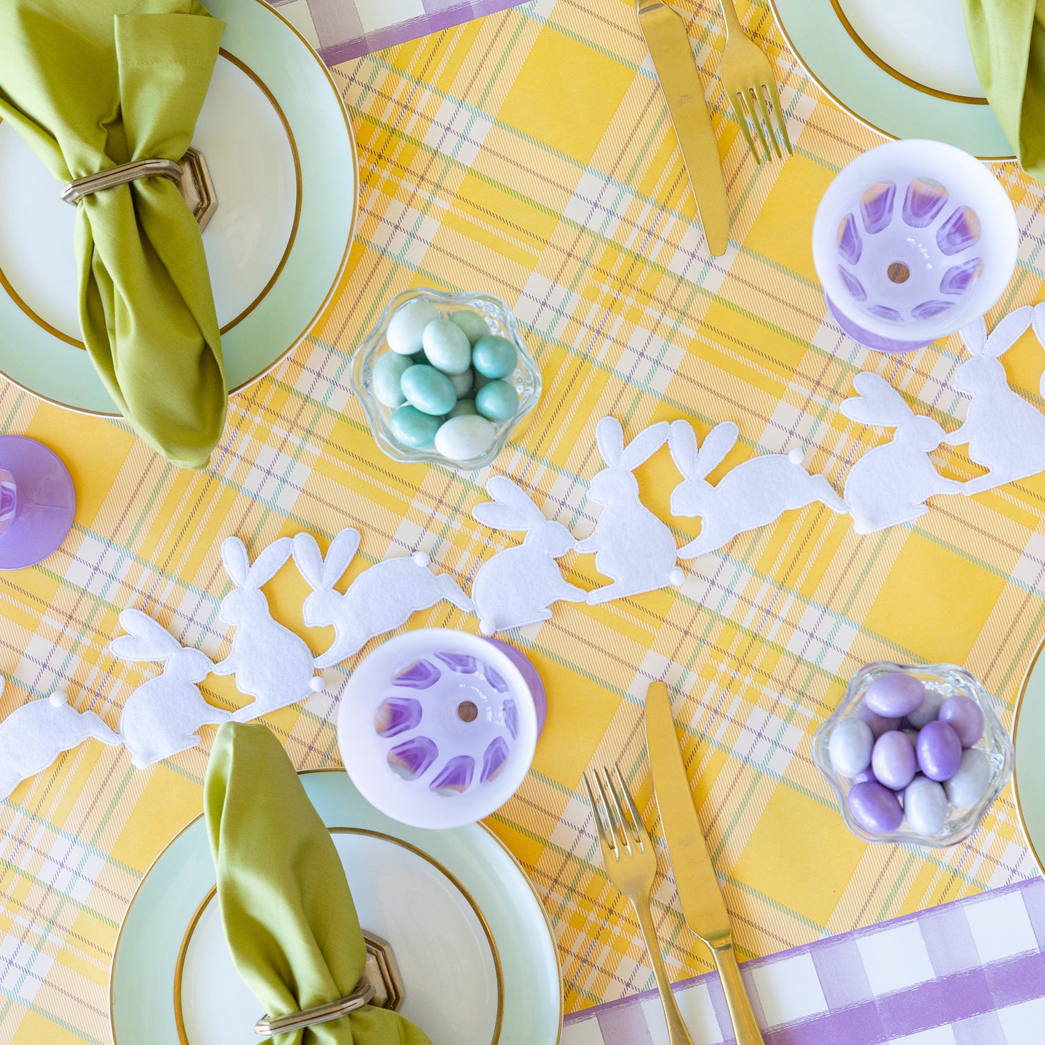 Rabbit Garland Ribbon with white appliqué rabbits made of felt  running down a table with a yellow plaid runner and purple glasses on it. 