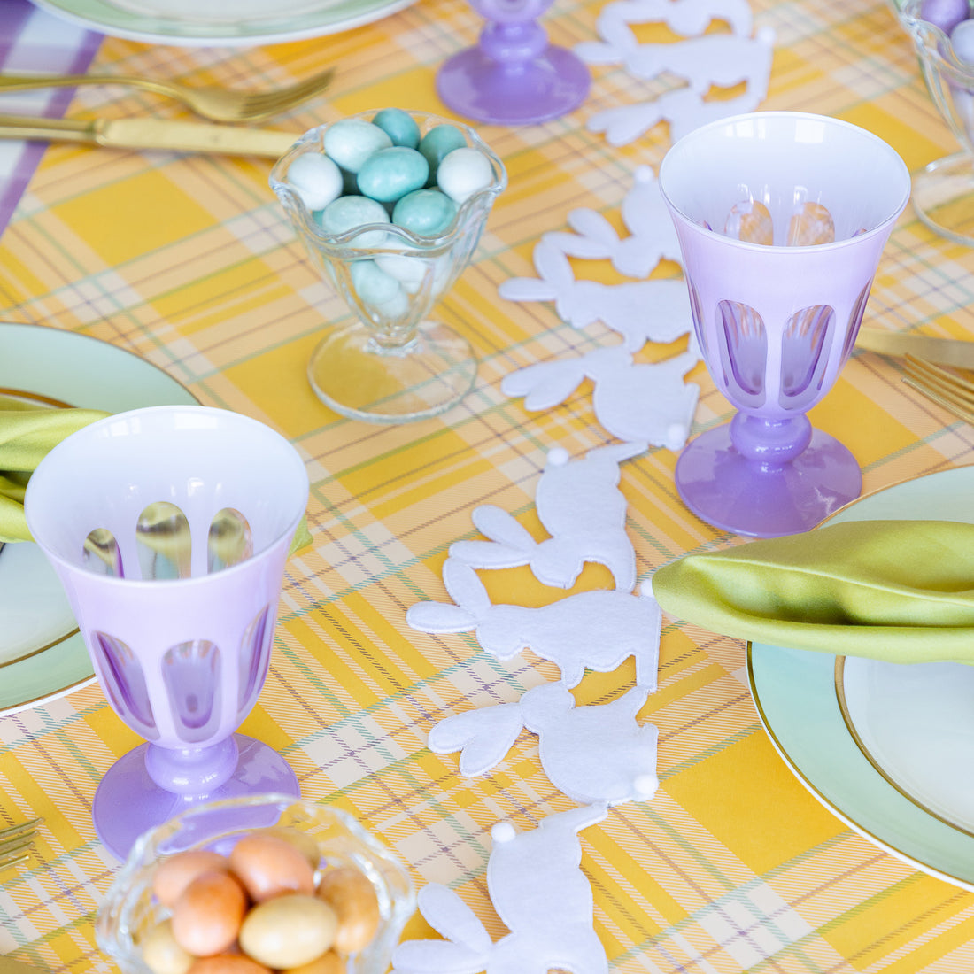 Rabbit Garland Ribbon with white appliqué rabbits made of felt  running down a table with a yellow plaid runner and purple glasses on it. 