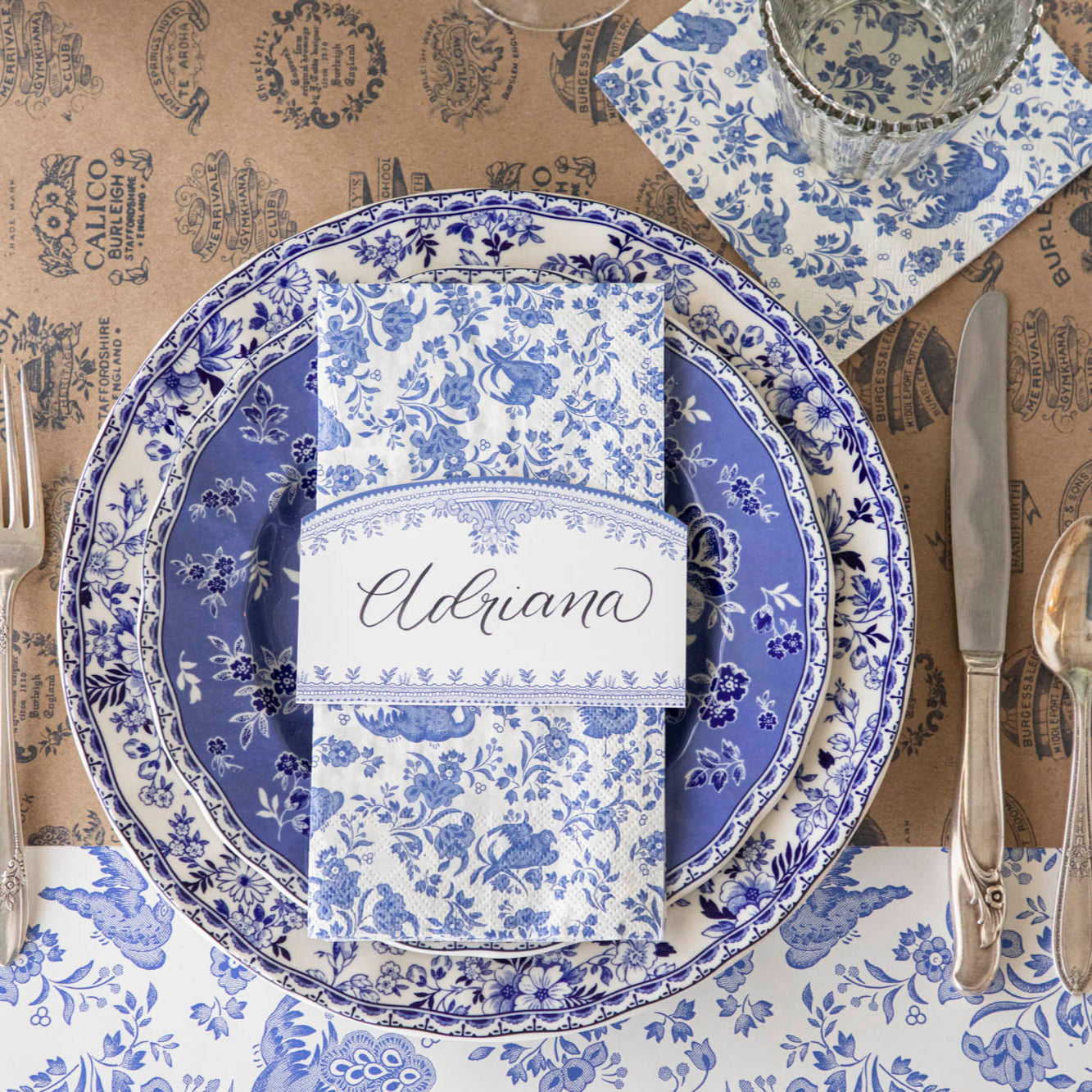 Blue Regal Peacock Guest Napkin on top of dinner plates with the Burleigh Blue Place Card on top.