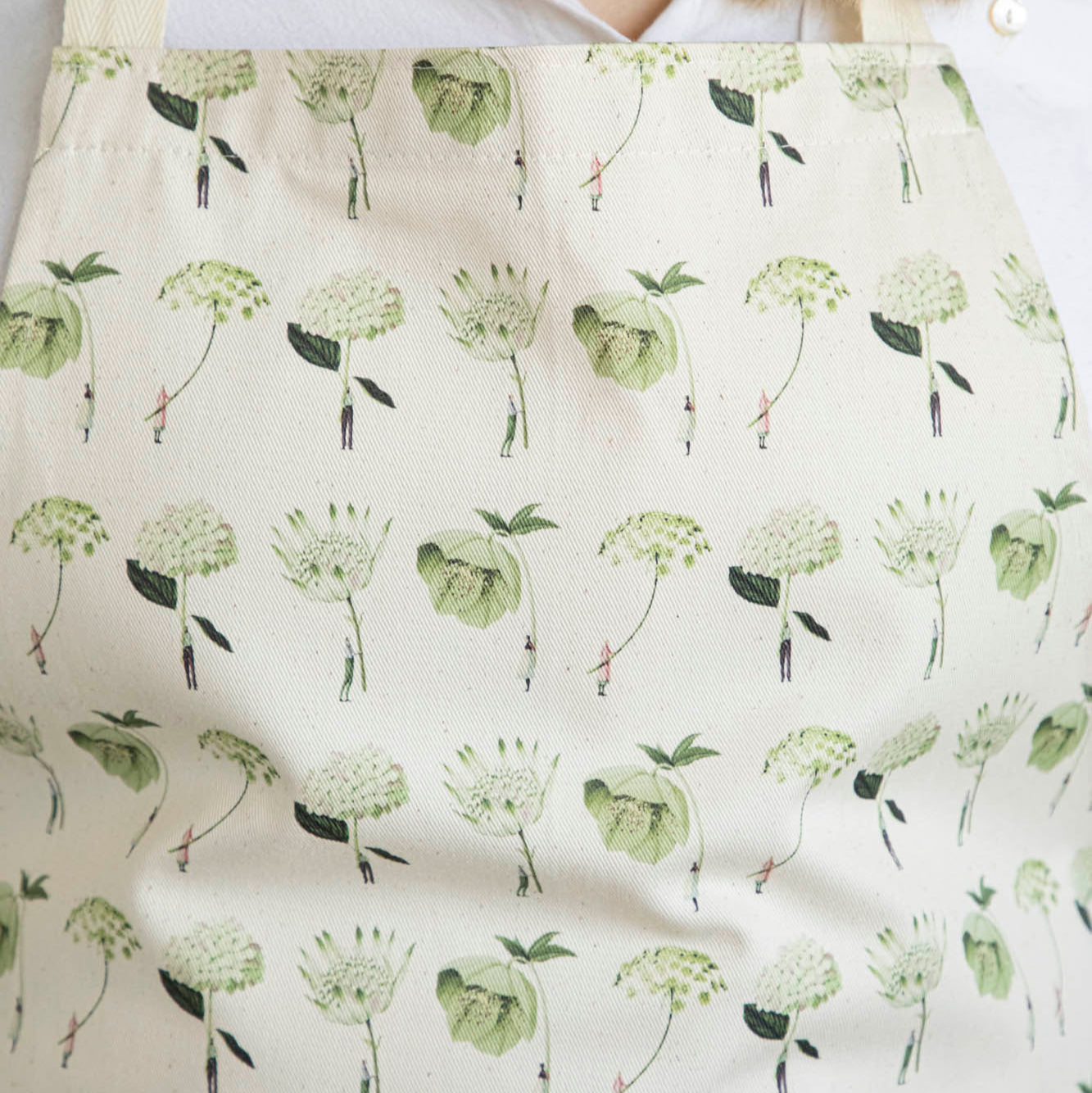 Close-up of a woman wearing the Green Flowers Apron by Laura Stoddart.