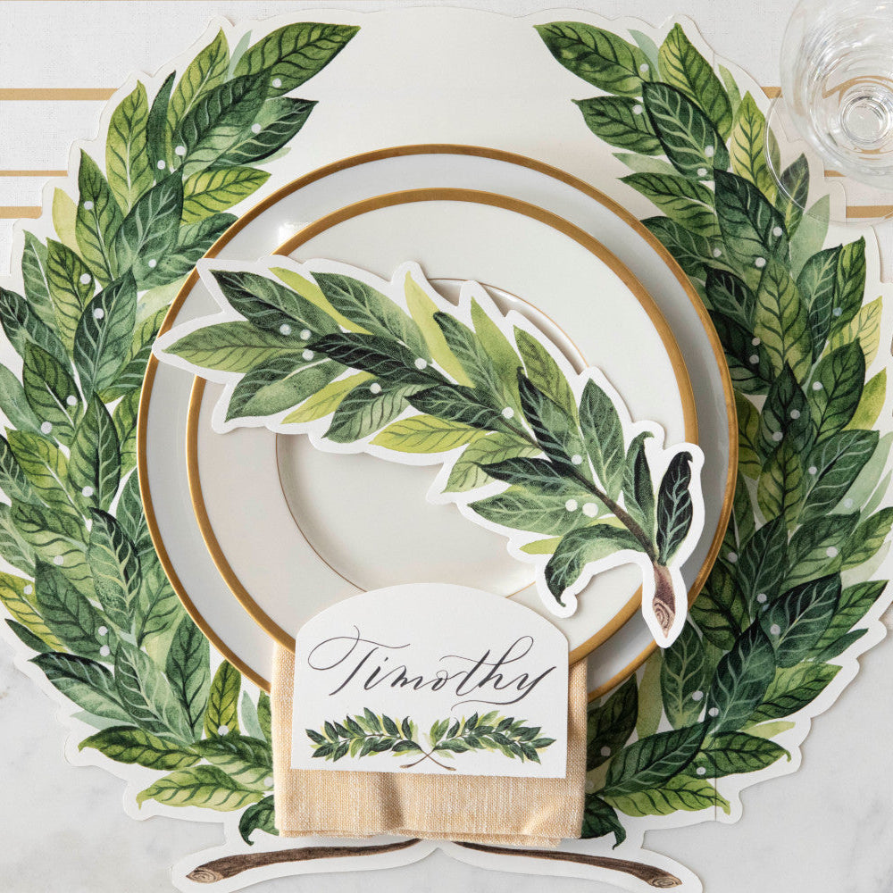 A Die-cut Green Laurel Wreath Placemat under an elegant place setting, from above.