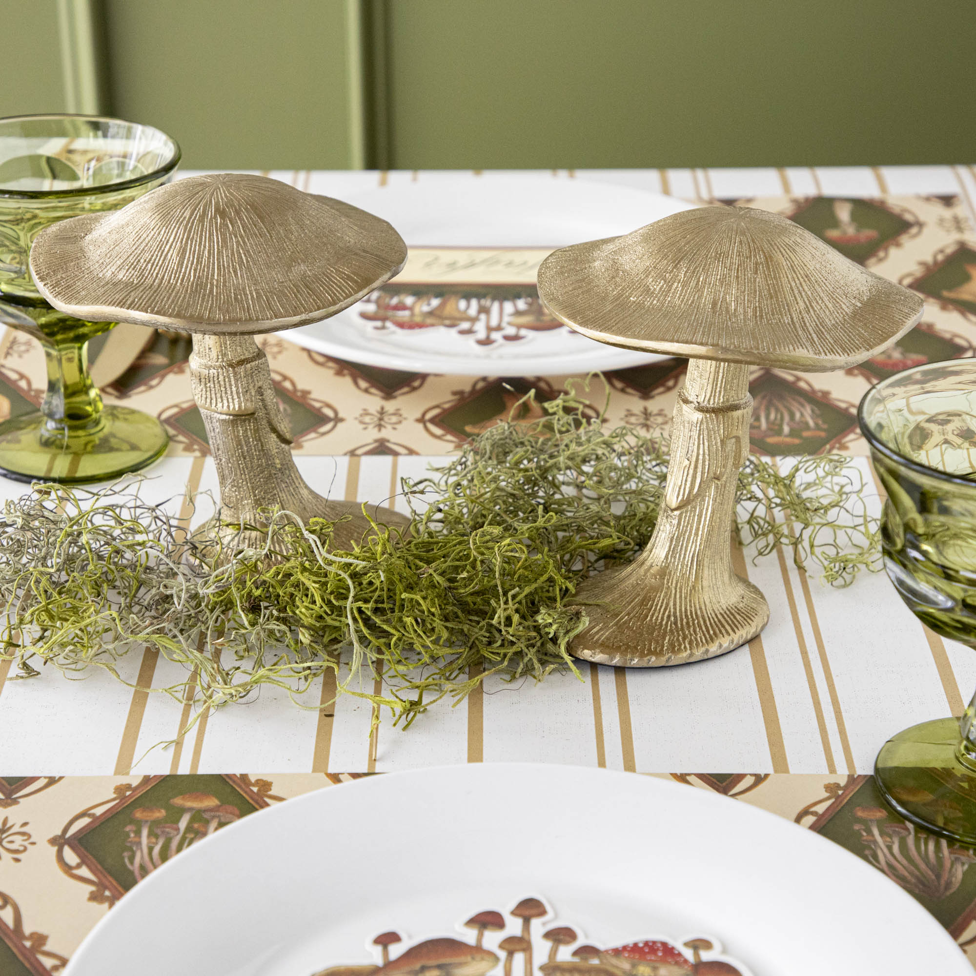 A gold metal mushroom figurine placed on a table with a harvest tablescape in the background.