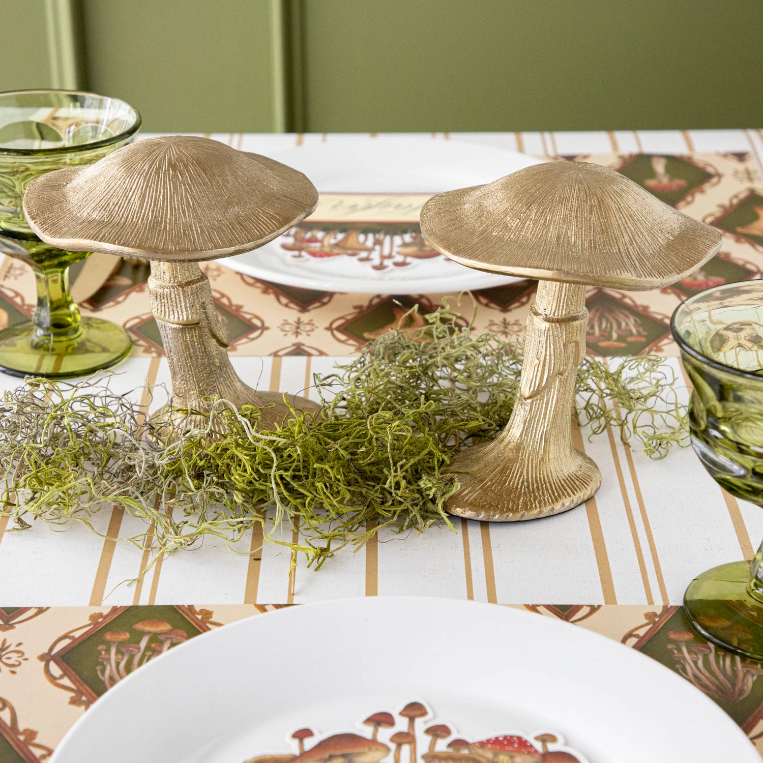 A gold metal mushroom figurine placed on a table with a harvest tablescape in the background.