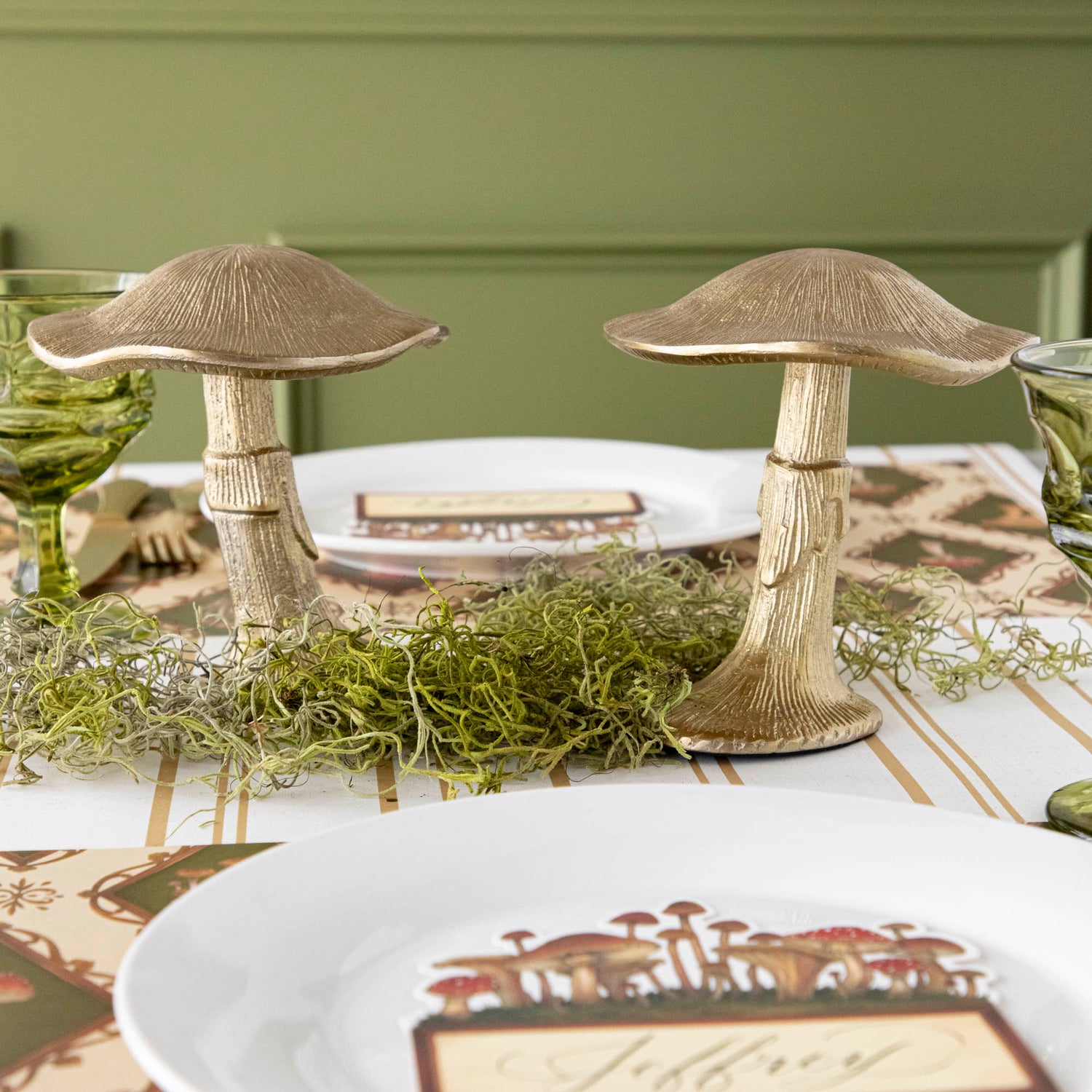 A gold metal mushroom figurine placed on a table with a harvest tablescape in the background.