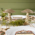 A gold metal mushroom figurine placed on a table with a harvest tablescape in the background.