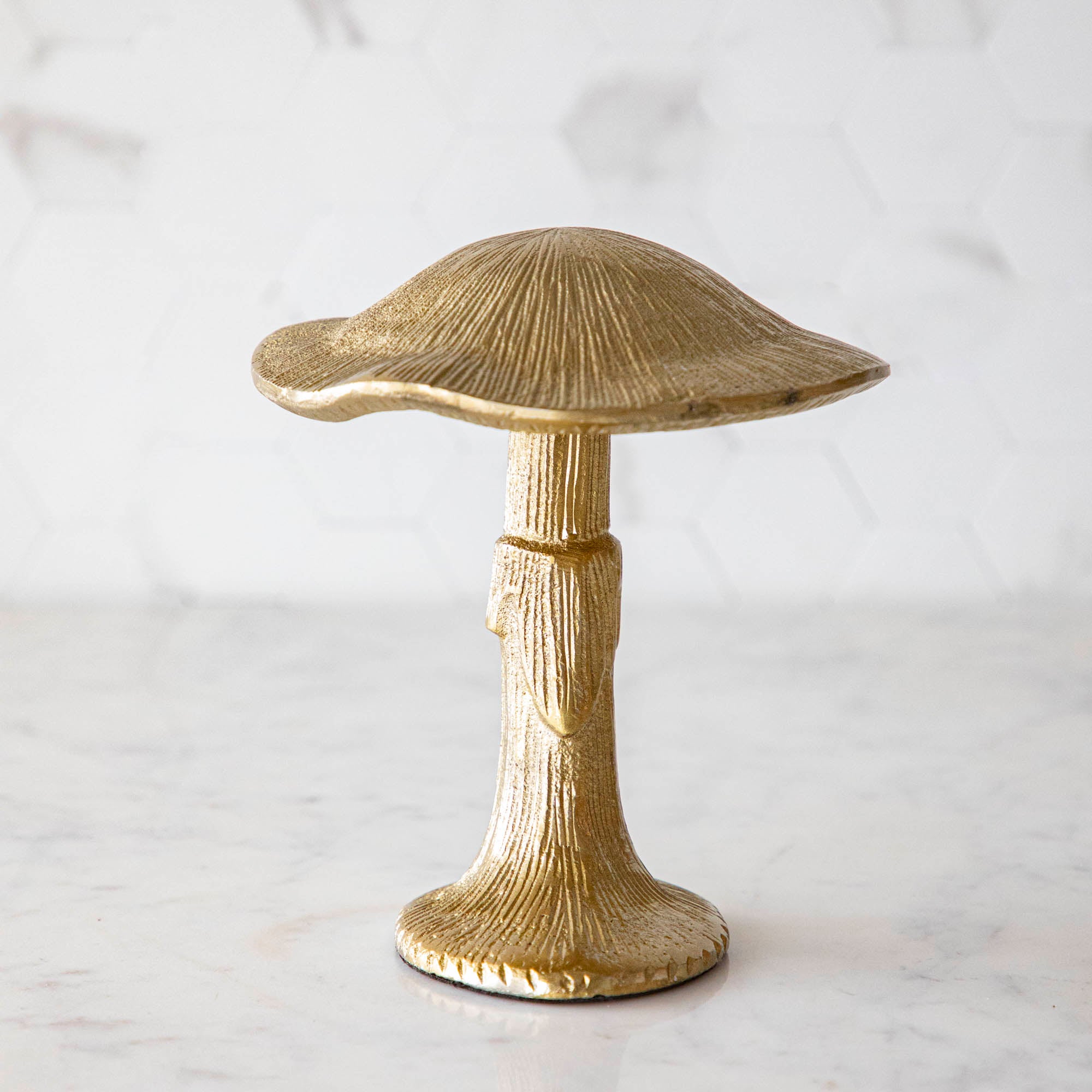 A gold metal mushroom figurine placed on a white marble table.