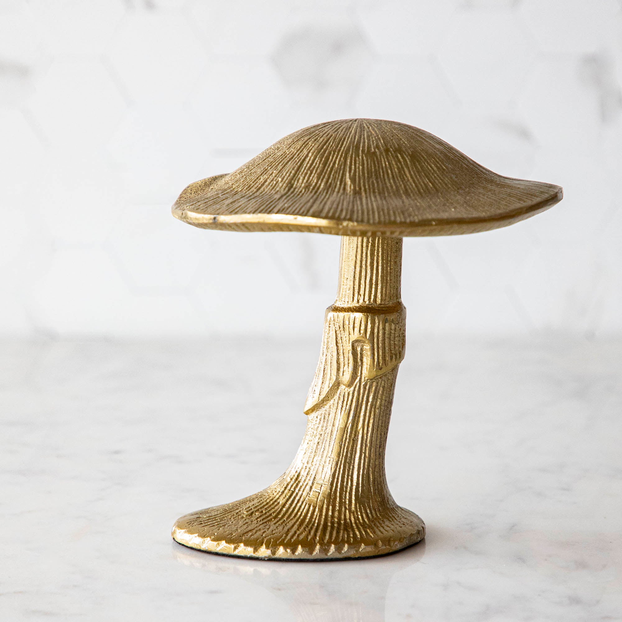 A gold metal mushroom figurine placed on a white marble table.