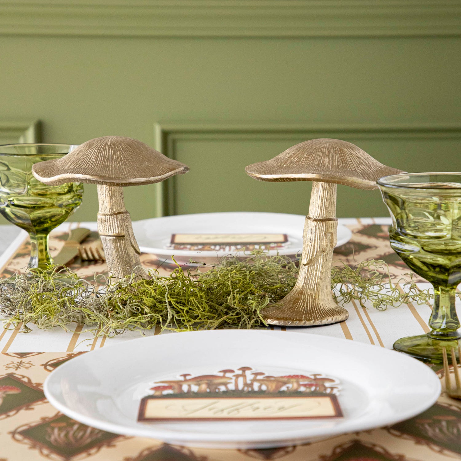 A gold metal mushroom figurine placed on a table with a harvest tablescape in the background.