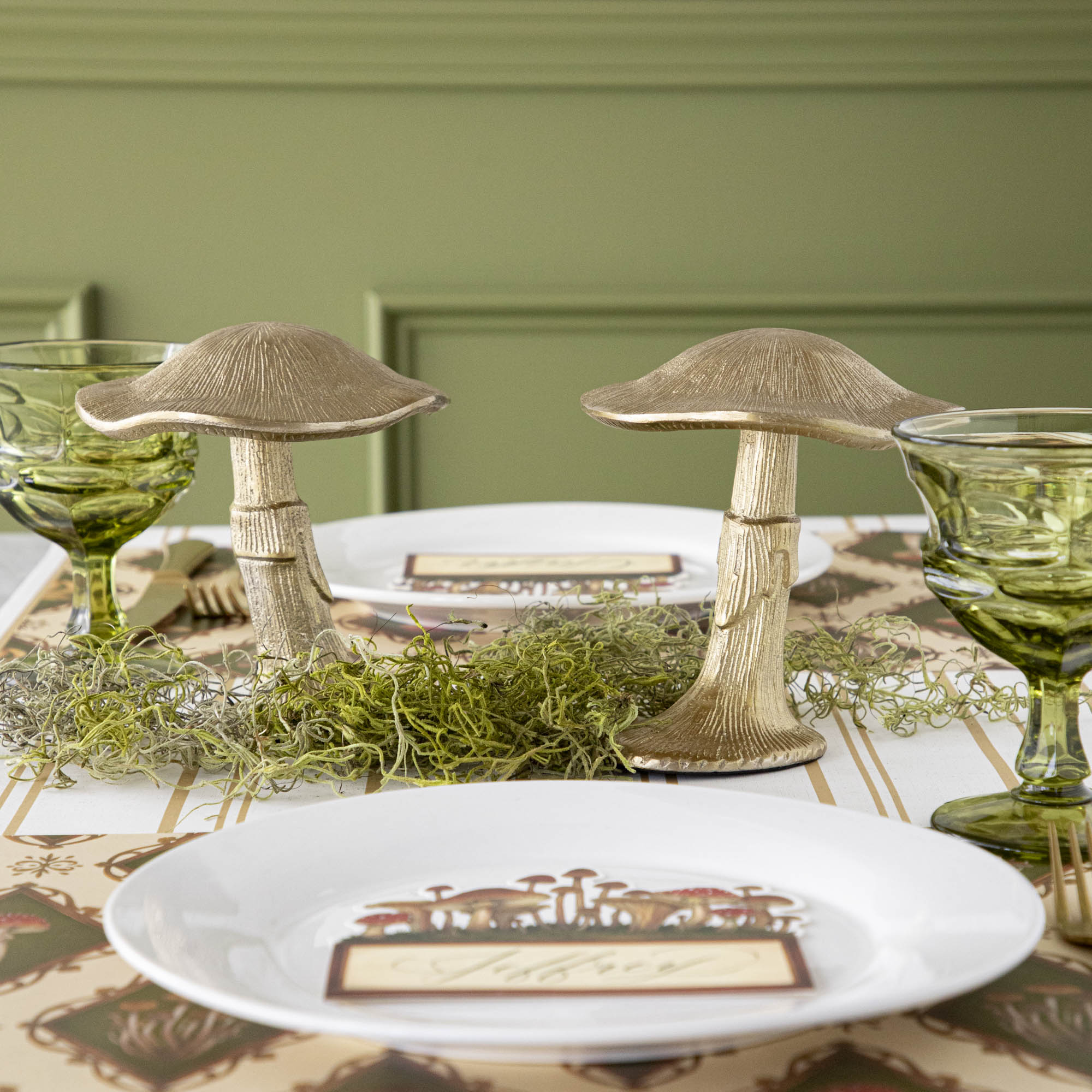 A gold metal mushroom figurine placed on a table with a harvest tablescape in the background.