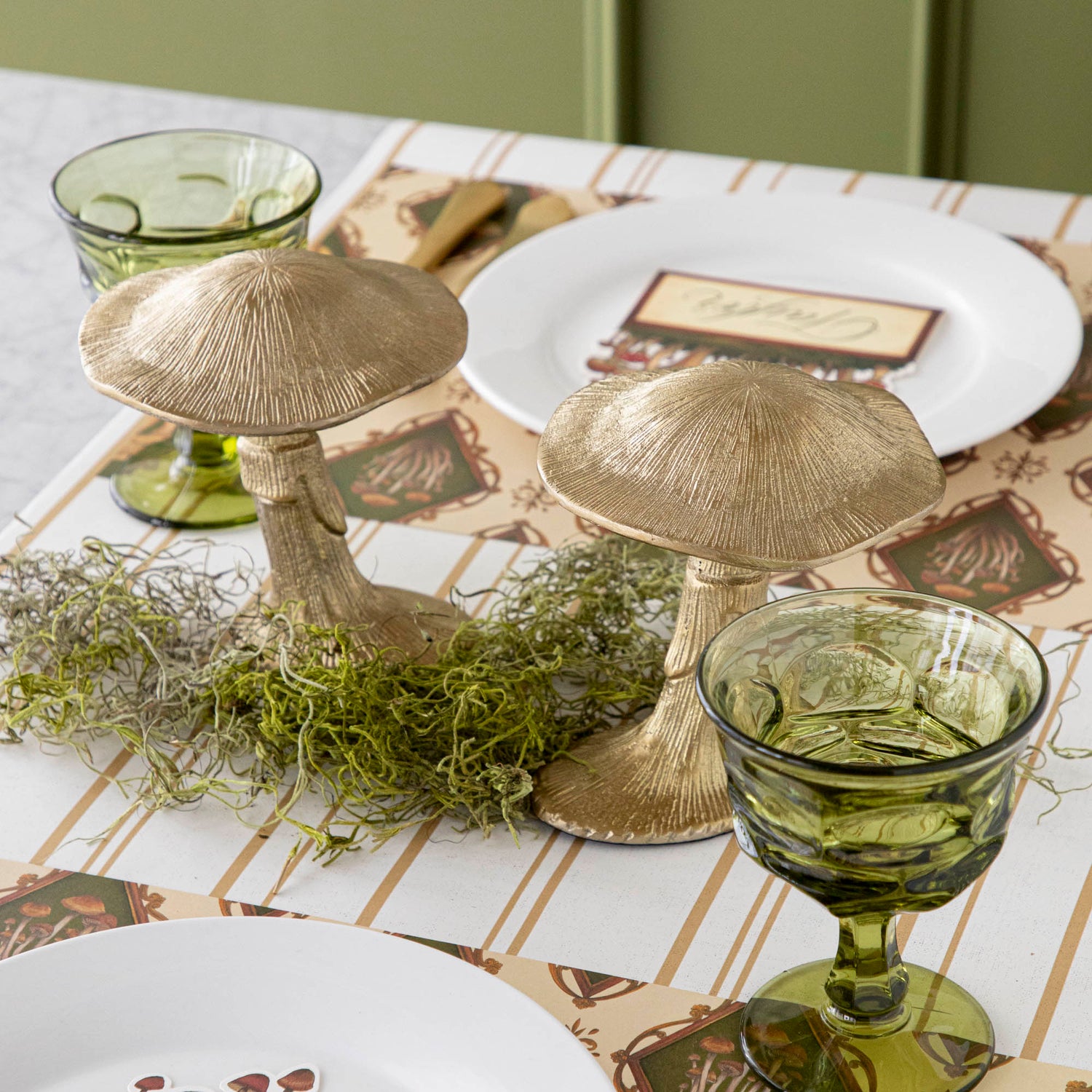 A gold metal mushroom figurine placed on a table with a harvest tablescape in the background.