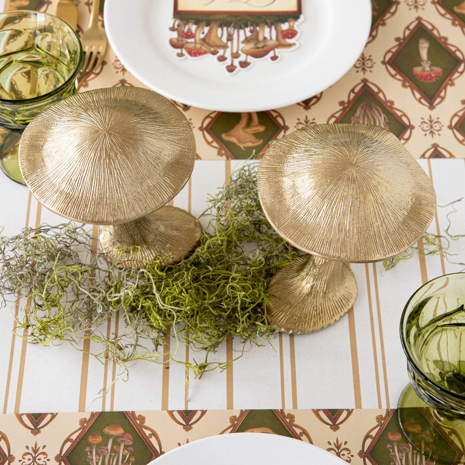 A gold metal mushroom figurine placed on a table with a harvest tablescape in the background.