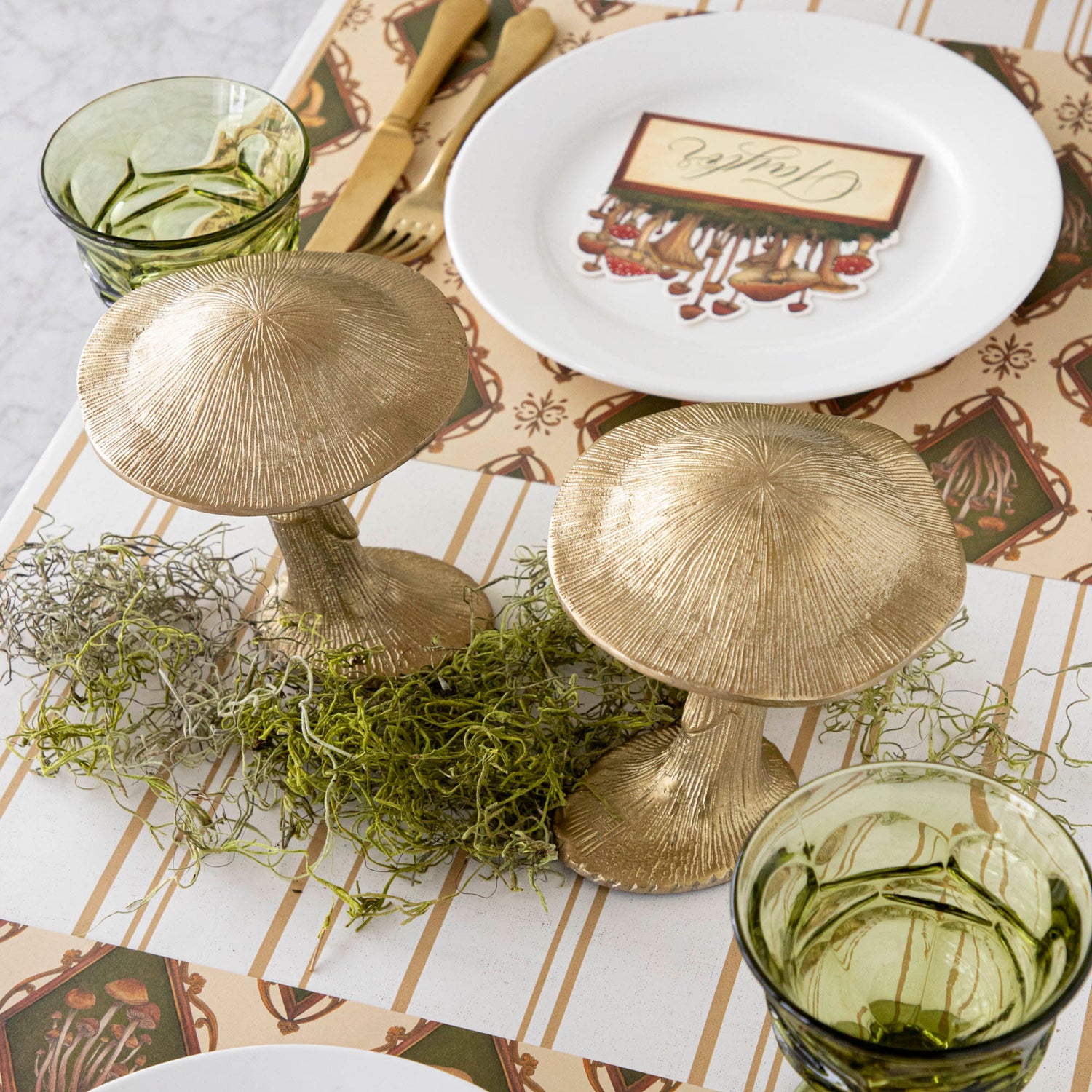 A gold metal mushroom figurine placed on a table with a harvest tablescape in the background.