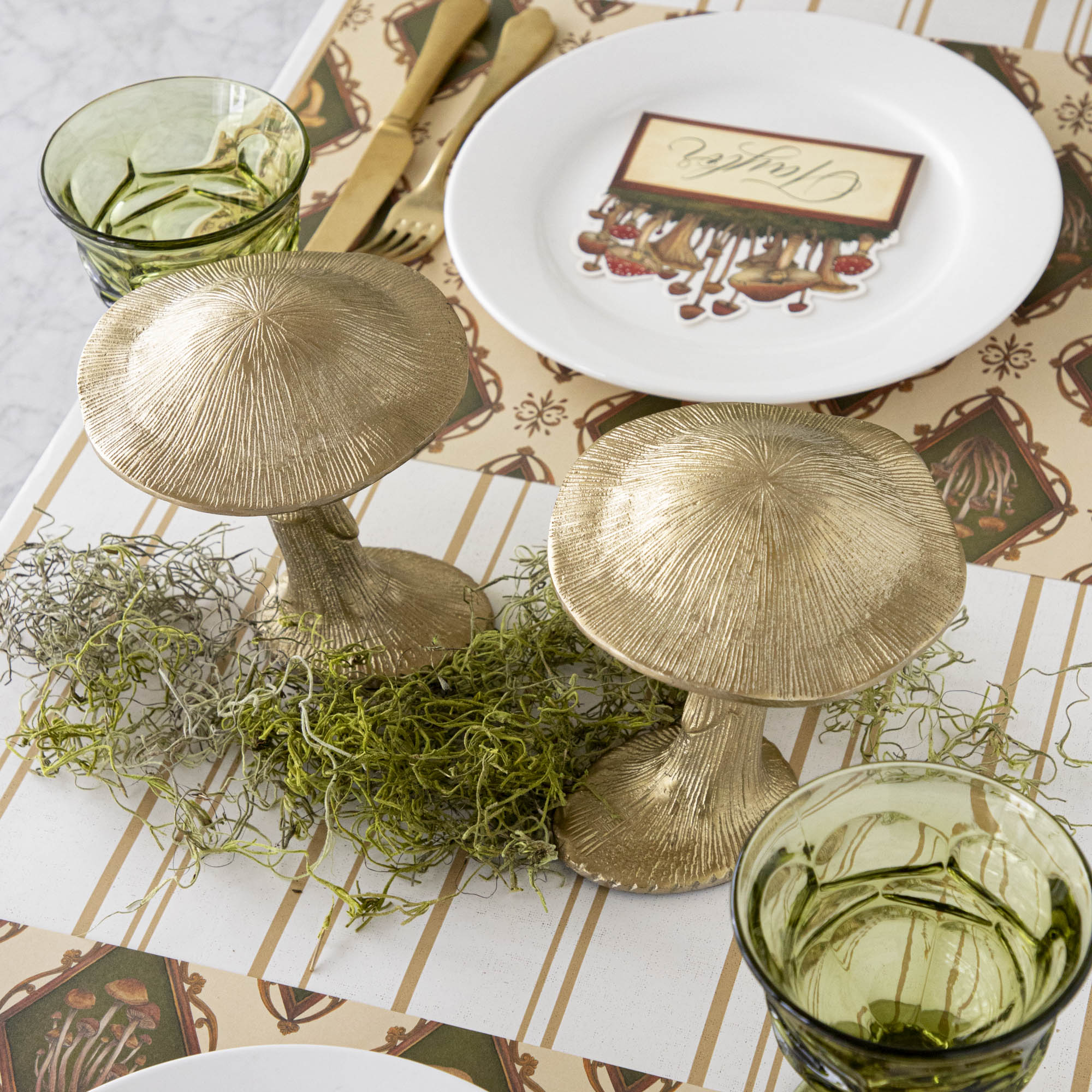 A gold metal mushroom figurine placed on a table with a harvest tablescape in the background.