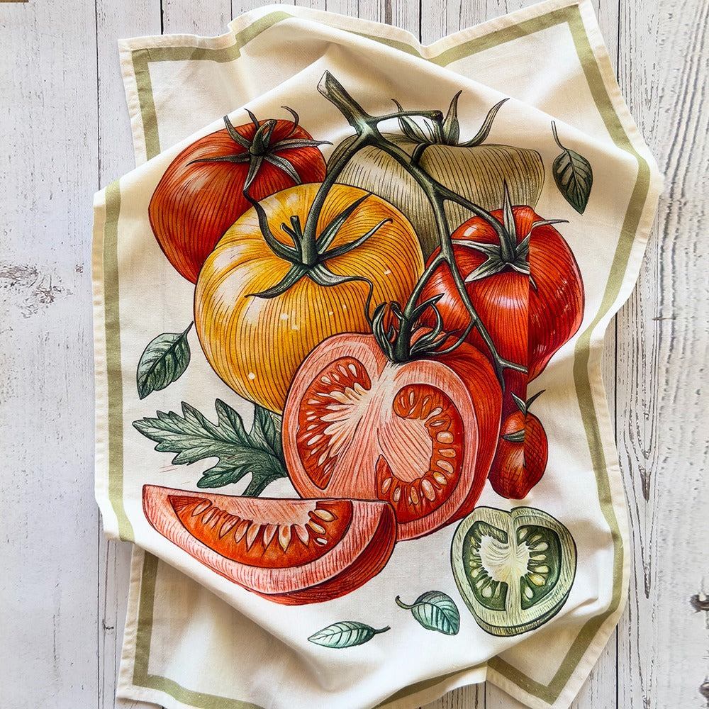 Decorative towel with a colorful illustration of tomatoes on a wooden surface.