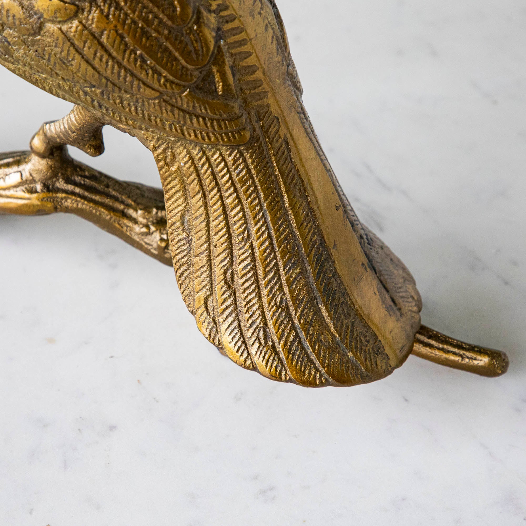 A bronze metal turkey on a branch decoration, placed on a dining table with green wall in the background.