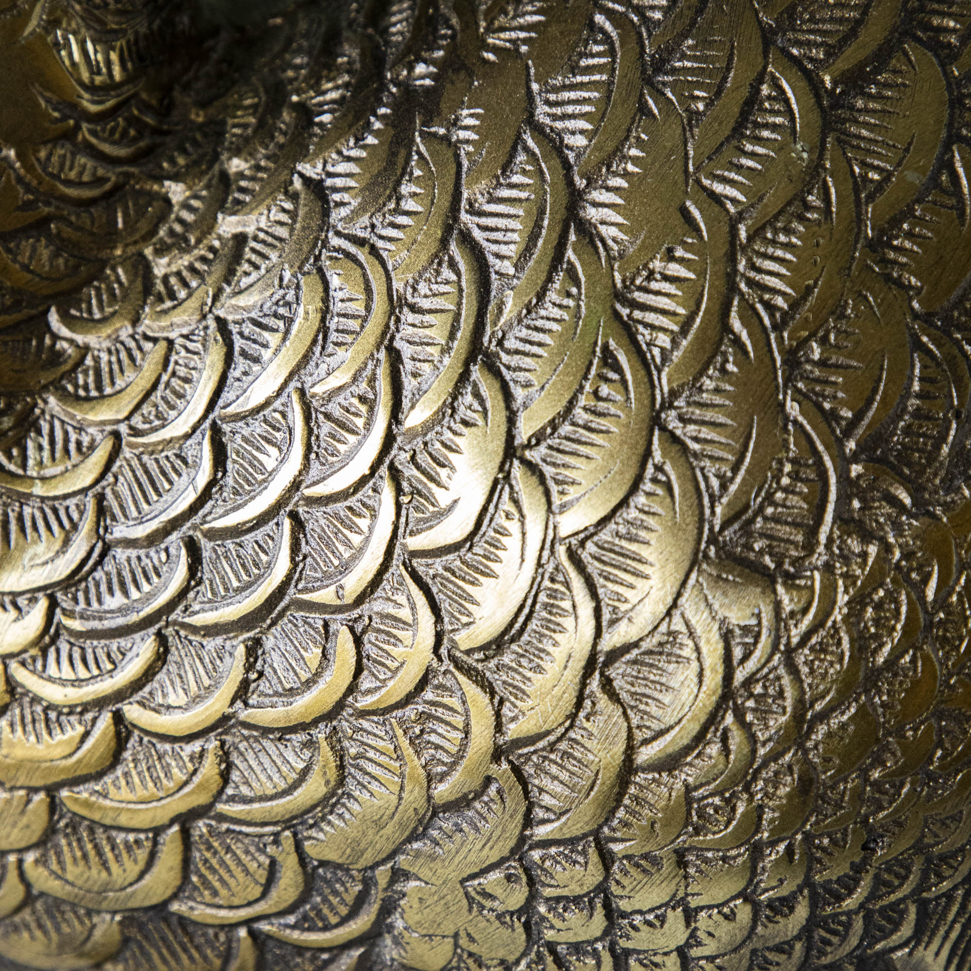 A bronze metal turkey on a branch decoration, placed on a dining table with green wall in the background.
