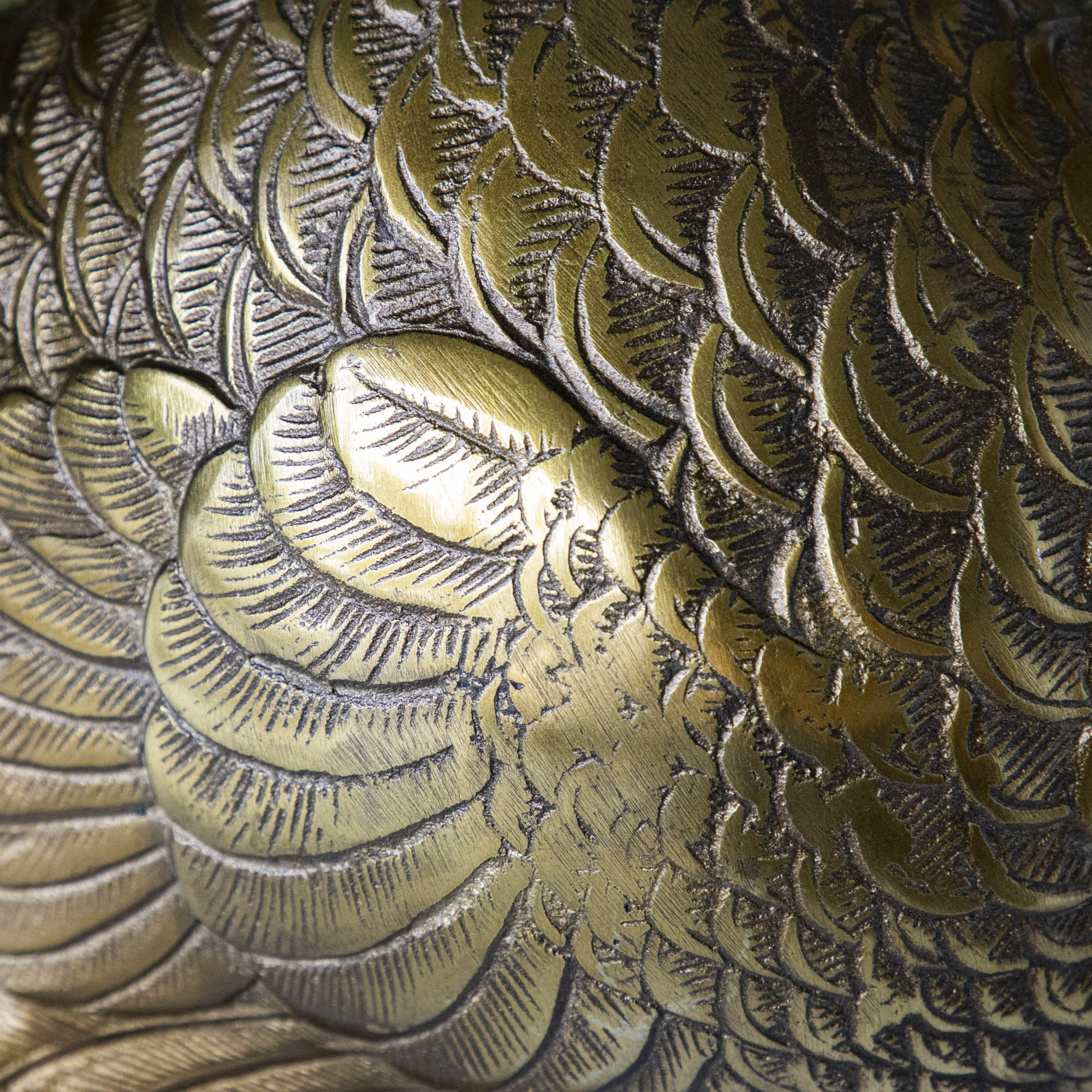 A bronze metal turkey on a branch decoration, placed on a dining table with green wall in the background.