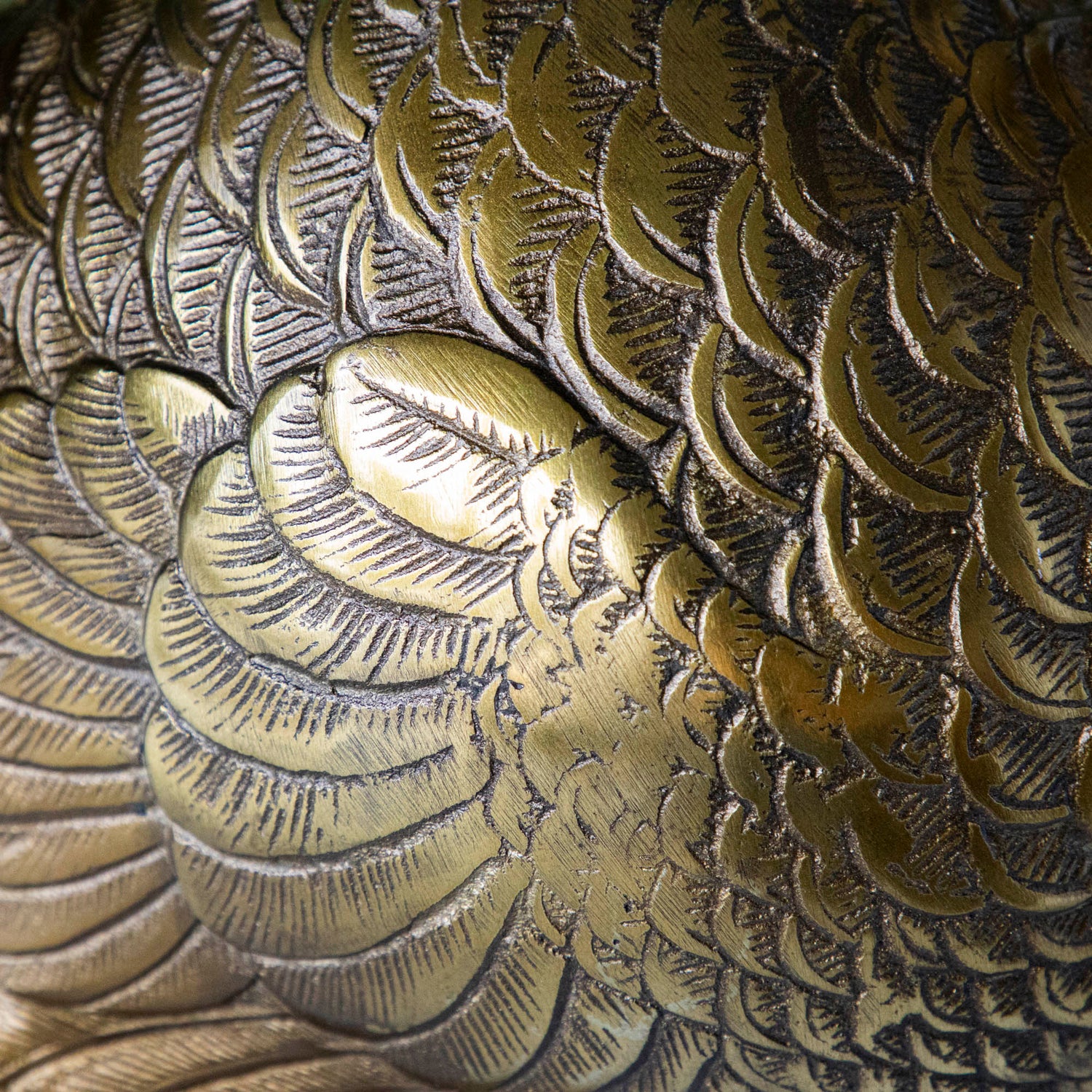 A bronze metal turkey on a branch decoration, placed on a dining table with green wall in the background.