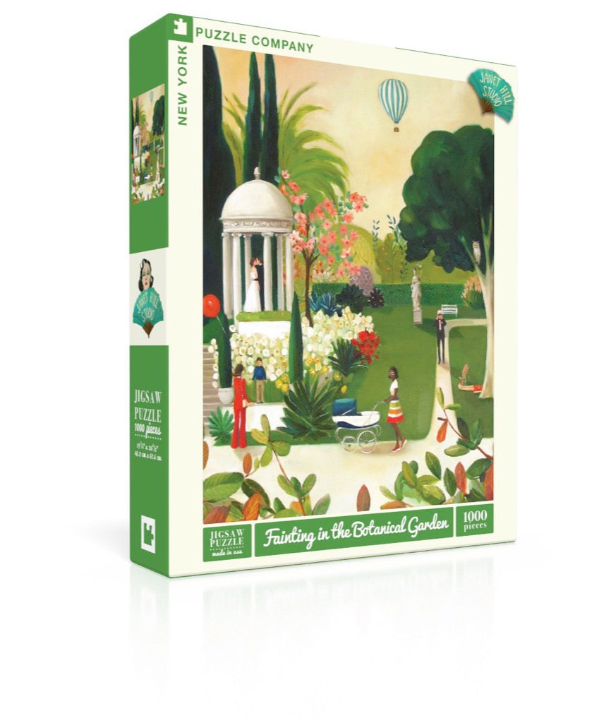A New York Puzzle Company jigsaw puzzle box featuring an illustration by artist Janet Hill of a serene botanical garden scene with a hot air balloon in the sky.