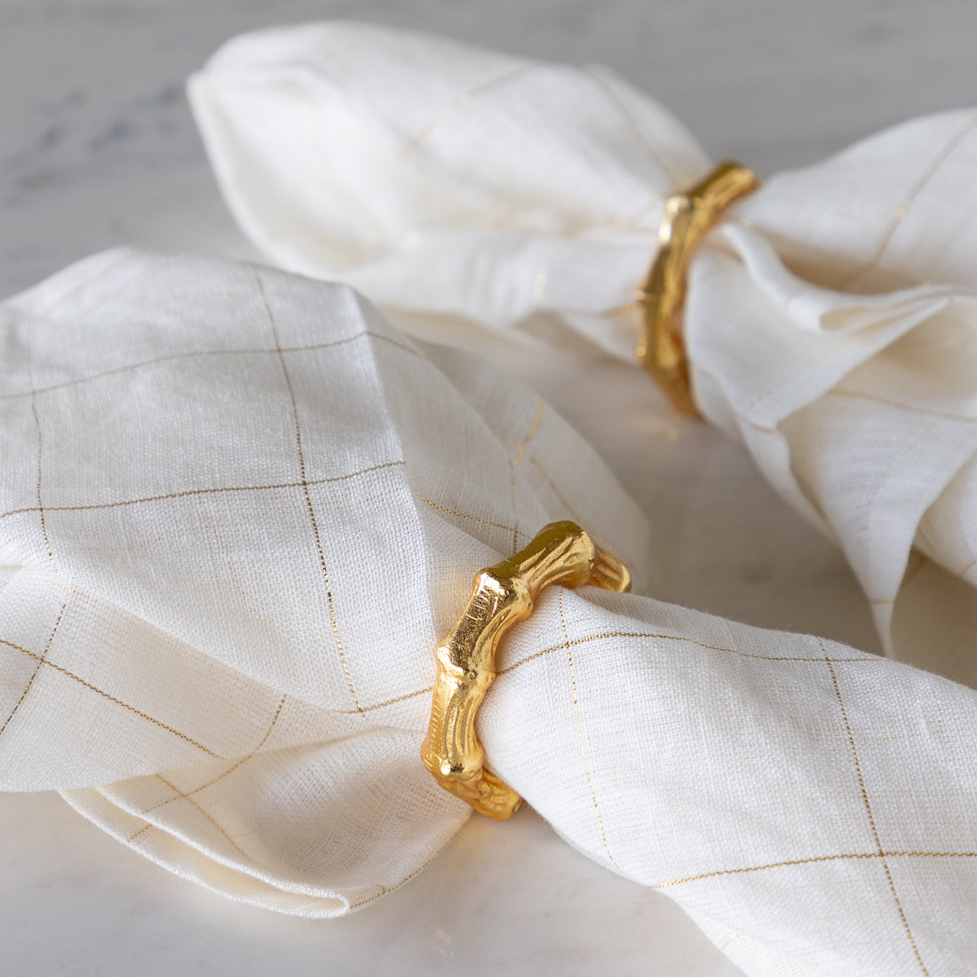 Aluminum Bamboo Napkin Rings around elegant white with gold stripes napkins.