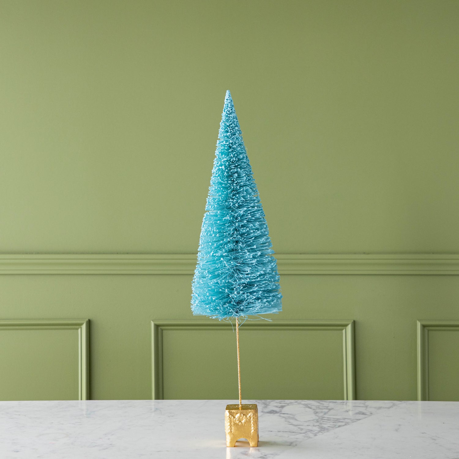 A 26" Cyan French Forest Sisal Tree with a gold base, on a marble table.