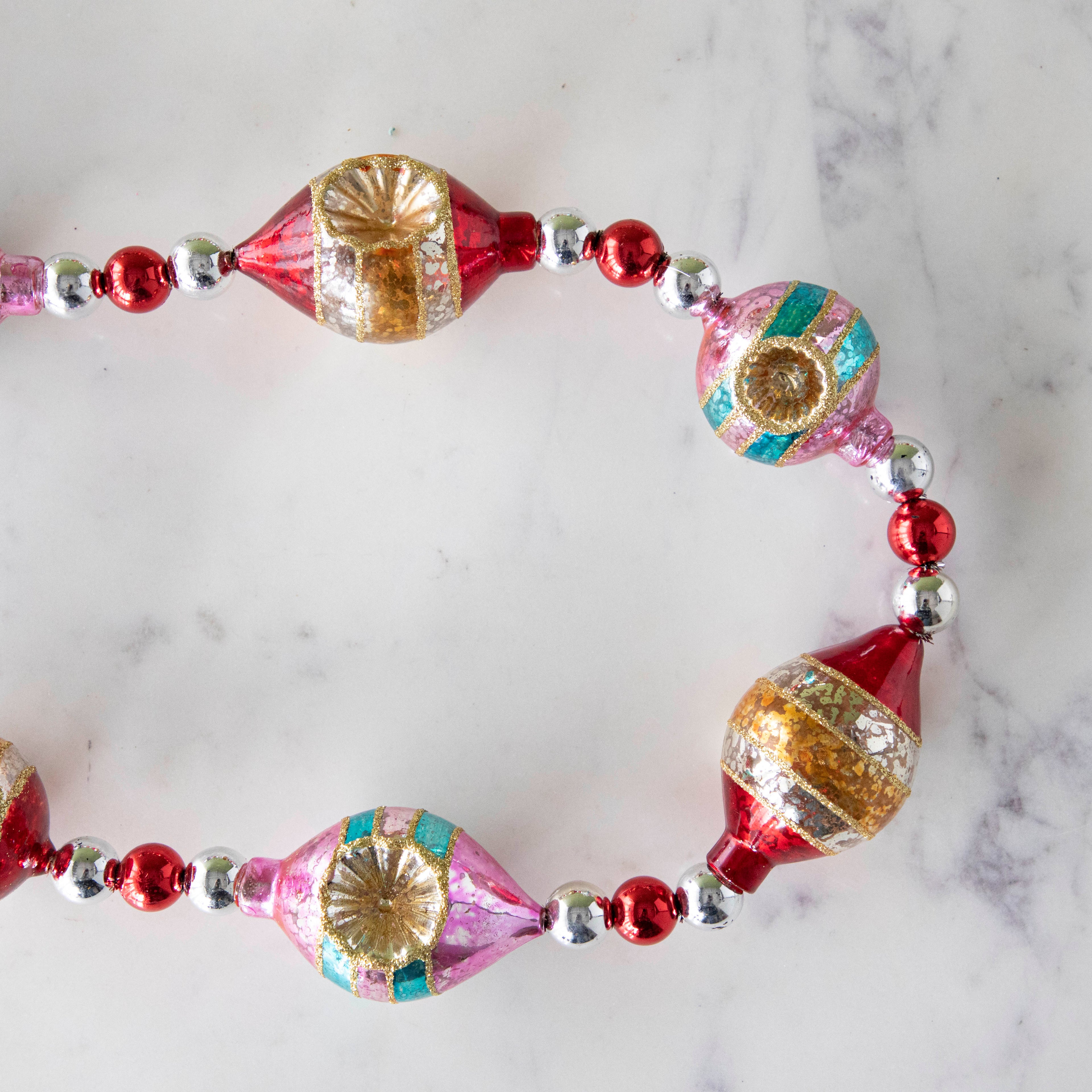 The Retro Tinsel and Glass Finial Garland on a marble table.