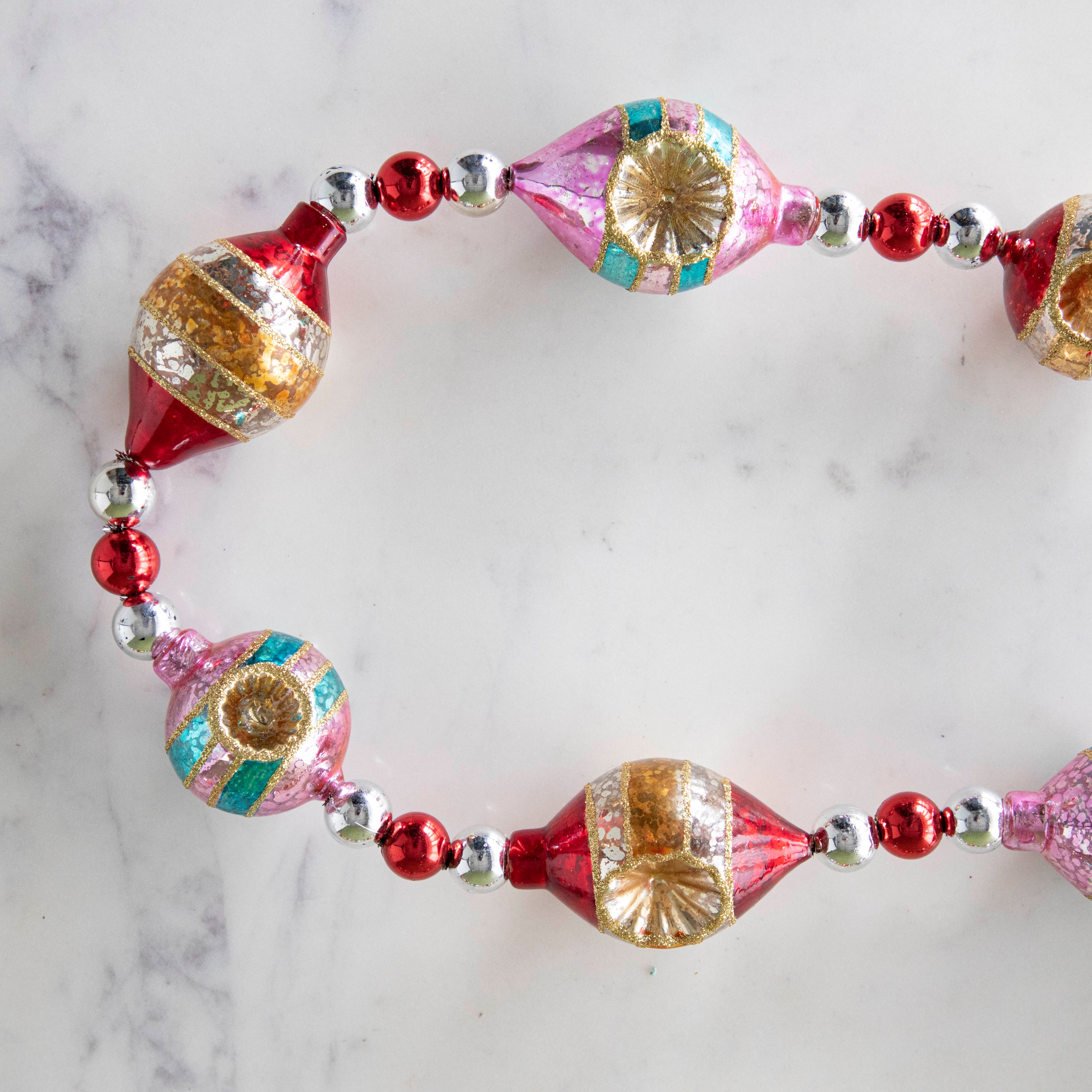 The Retro Tinsel and Glass Finial Garland on a marble table.