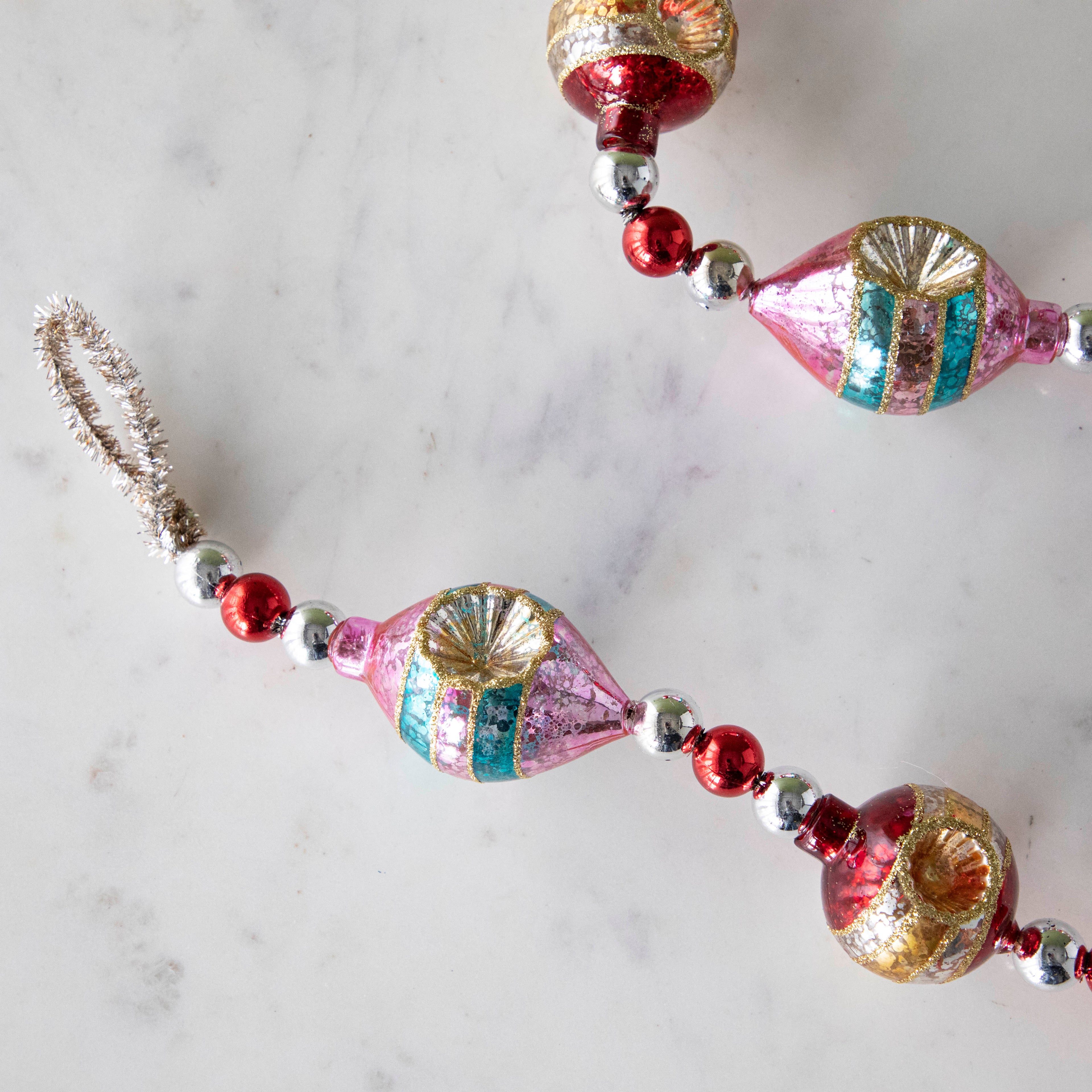 The Retro Tinsel and Glass Finial Garland on a marble table.