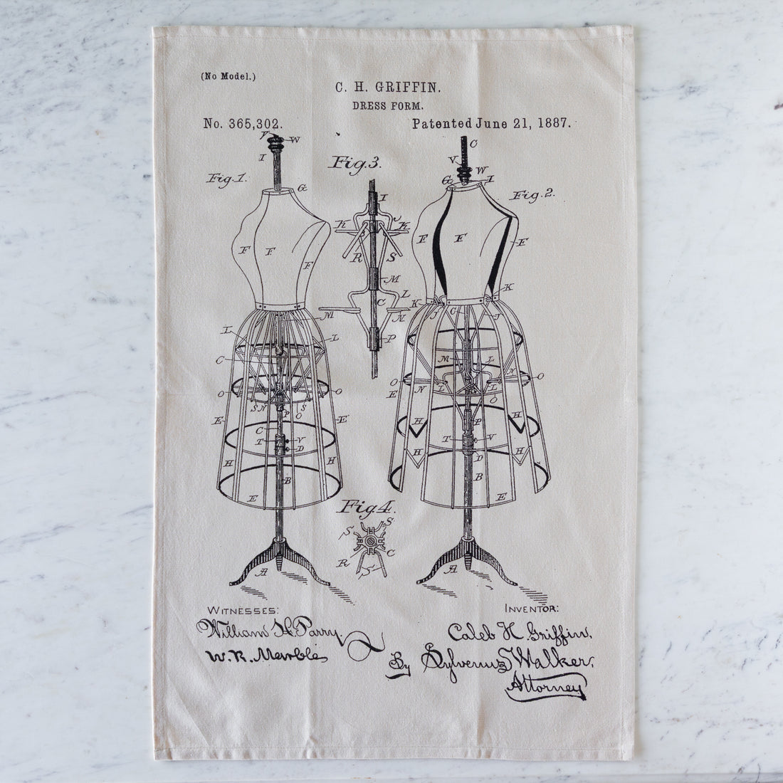 Tea towel with dress form patent design on a textured surface.