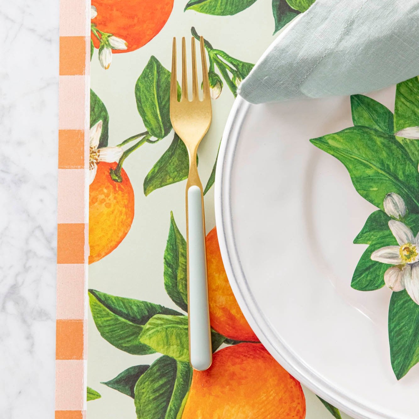 Close up of the Orange Orchard Placemat with a seafoam and gold fork and Orange Painted Check Runner underneath.