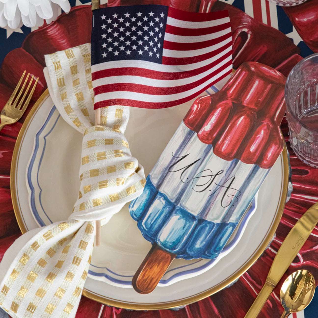 A patriotic place setting featuring a Rocket Pop Table Accent with "USA" written on it resting on the plate.