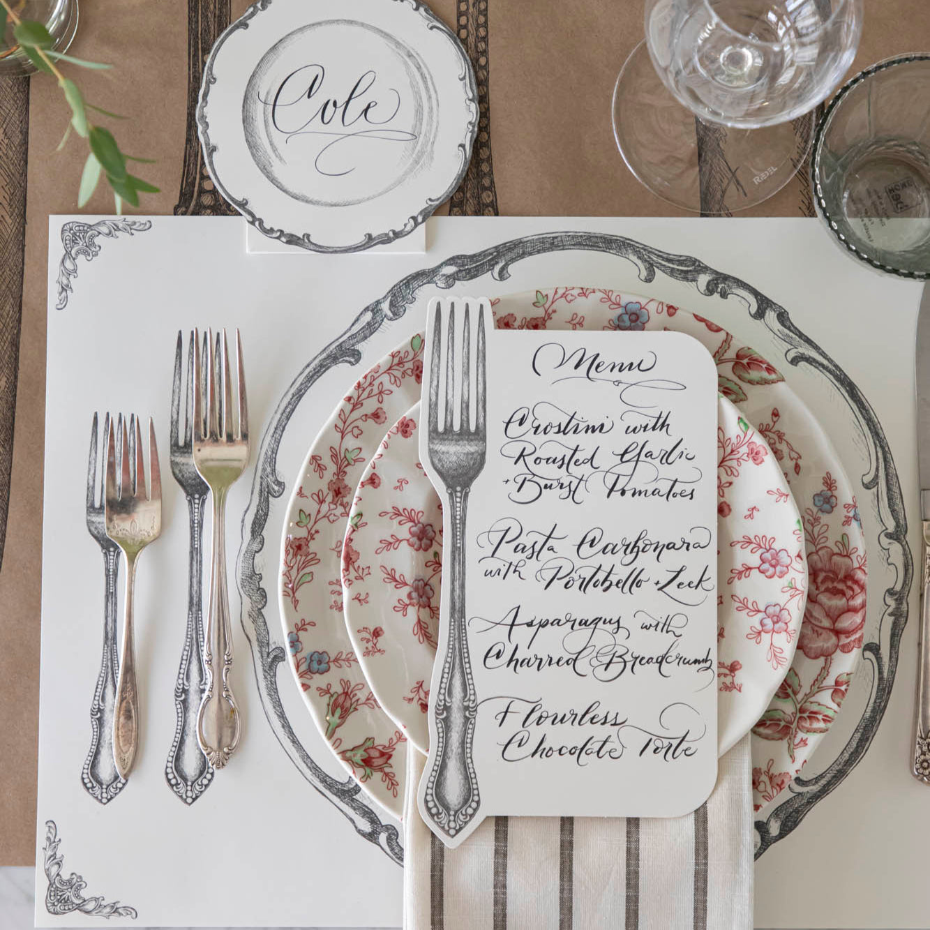 Vintage Fork Table Card with a menu written on it, resting on dinner plates on a table setting for one.