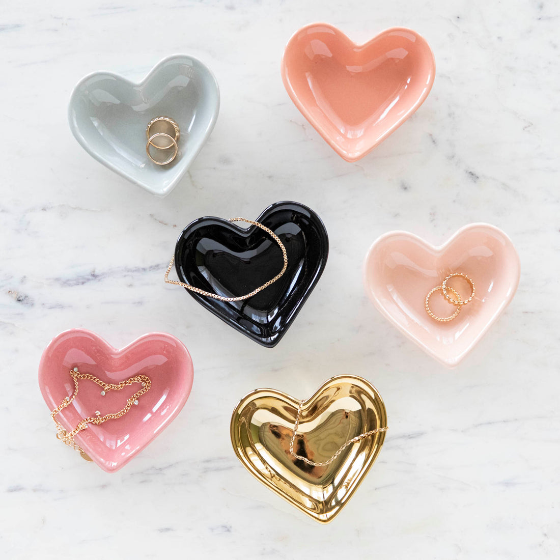 A collection of heart-shaped pinch bowls in various colors including blue, black, pink, and gold.