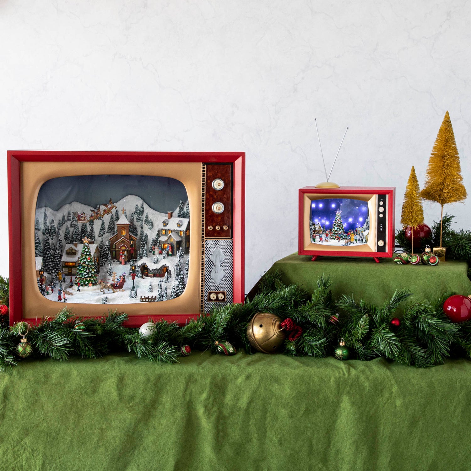 The Retro Oversized TV Scene with Adaptor and Retro TV Scene on top of a green tablecloth, surrounded by festive garland and trees.
