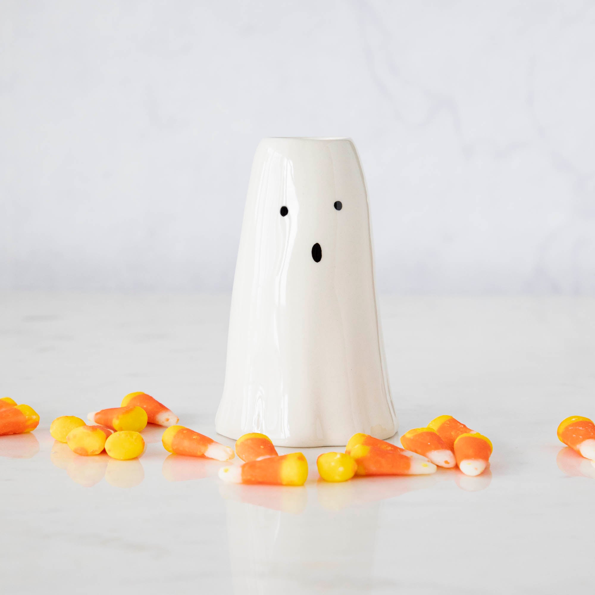 A Phantom Candleholder on a table surrounded by candy corn.