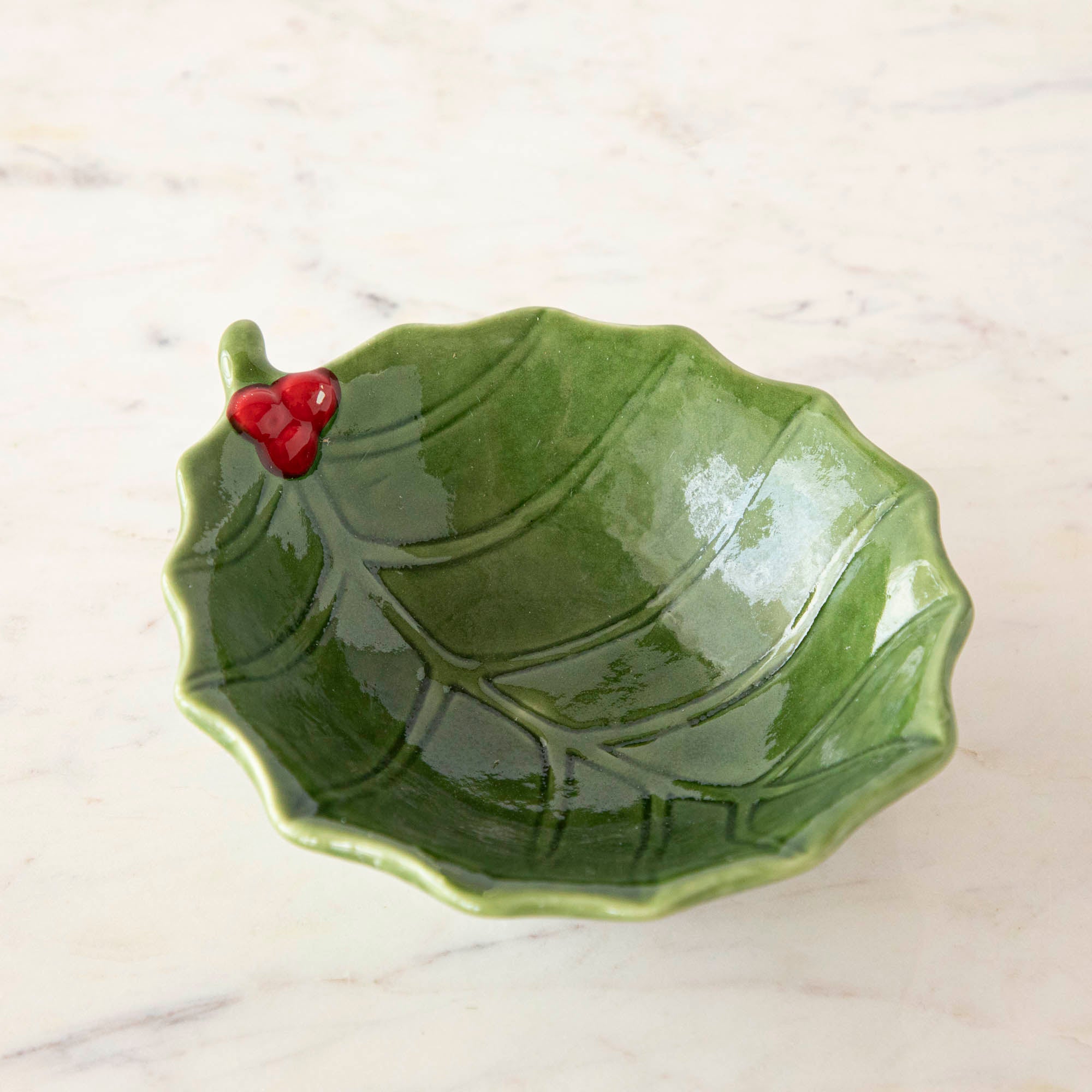 A green stoneware bowl with a holly leaf pattern.