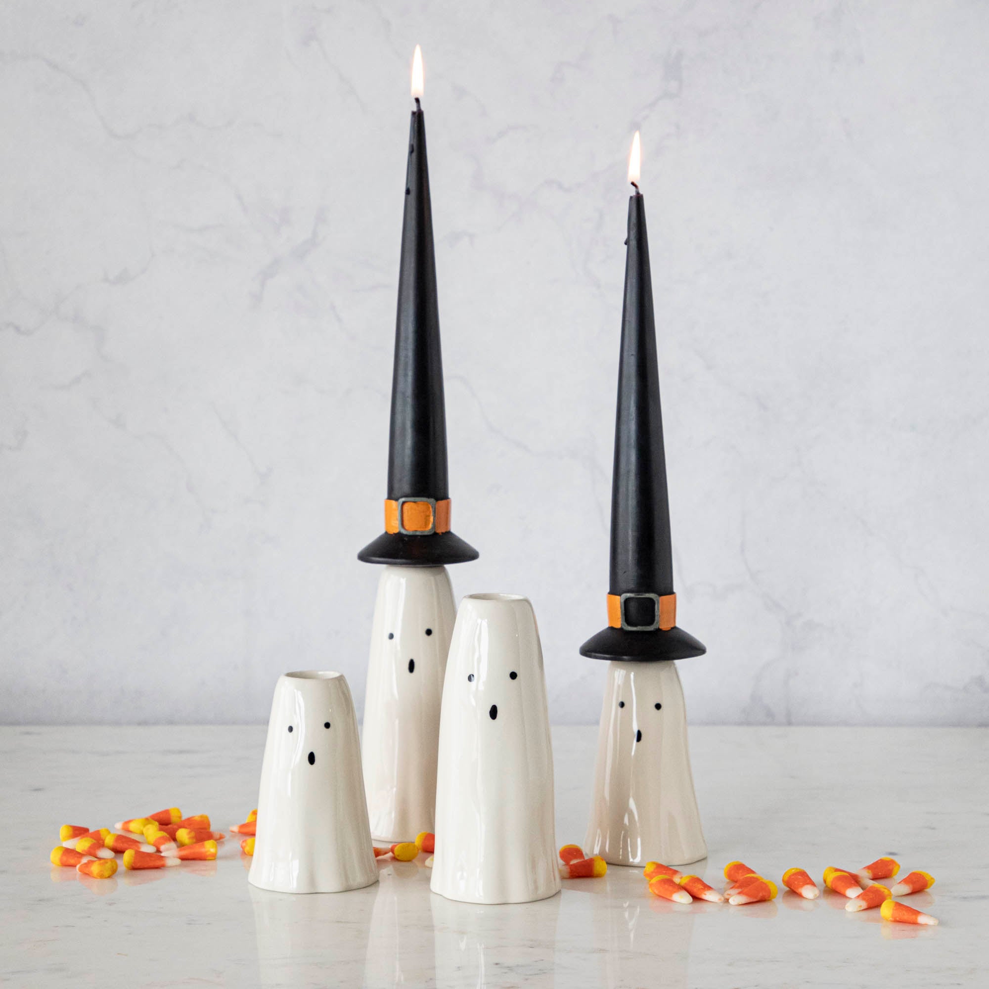 Four Phantom Candleholders from Accent Decor with witch hat candles, on a table surrounded by candy corn. 