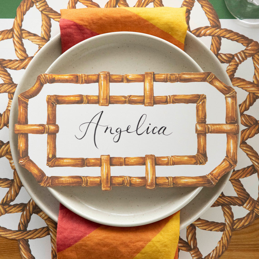 Top-down view of an elegant place setting featuring a Bamboo Table Card labeled "Angelica" resting on the plate.