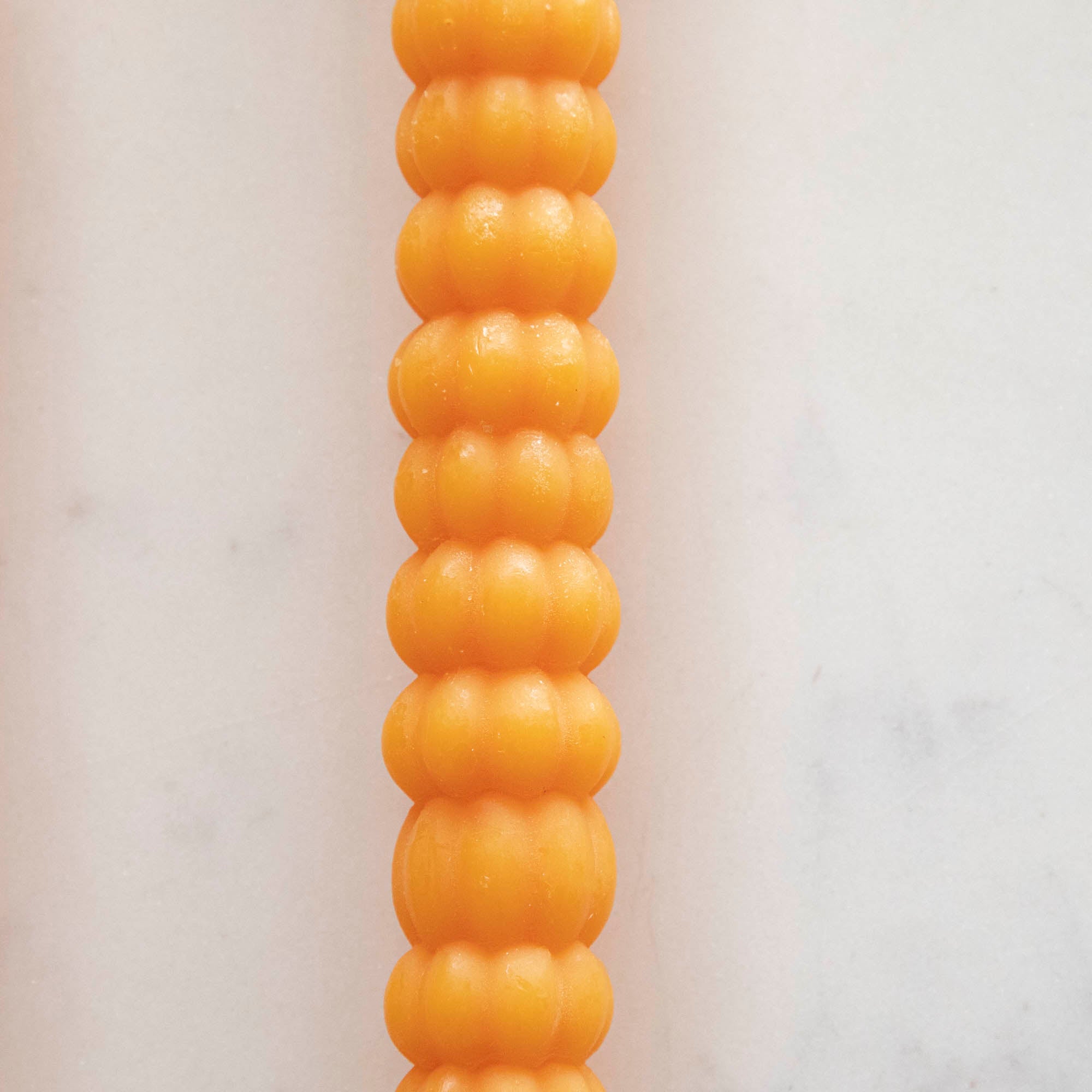 Close-up of the orange pumpkin taper candle.